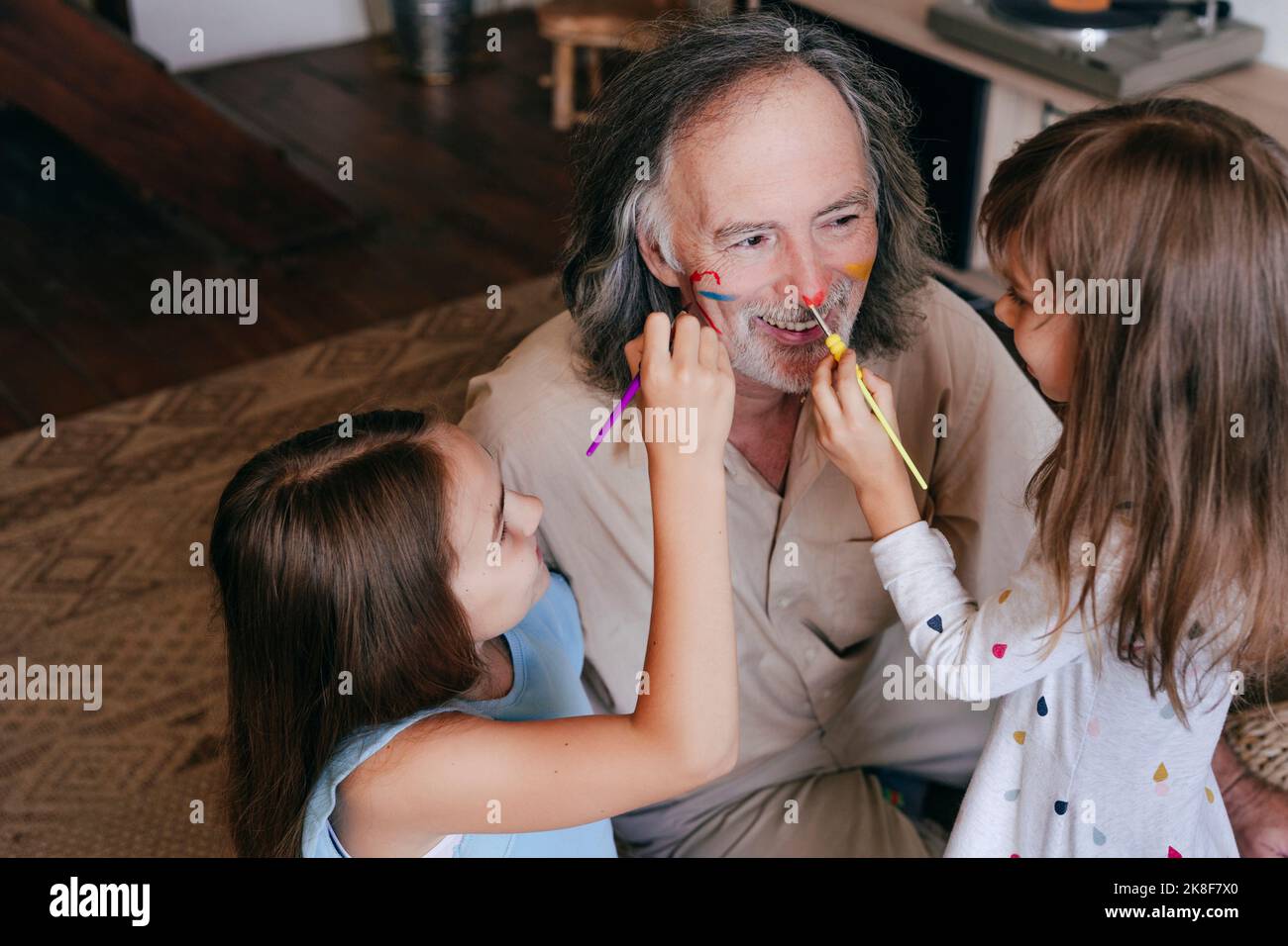 Les enfants joueurs s'amusent à peindre le nez du grand-père à la maison Banque D'Images