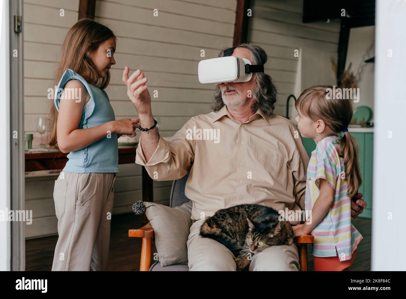 Grand-père portant un simulateur de réalité virtuelle gestant par des petits-enfants à la maison Banque D'Images