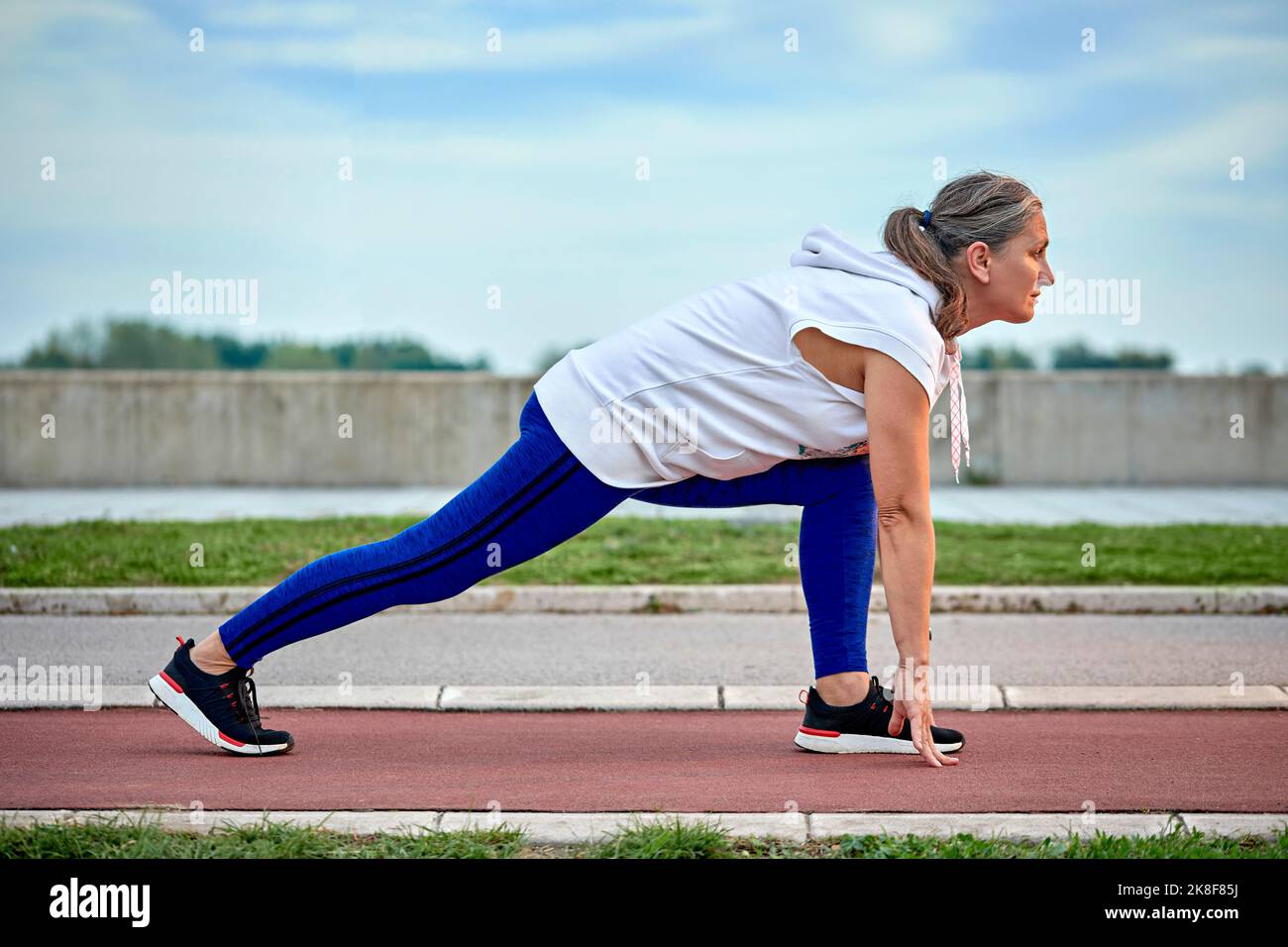 Femme mûre se préparant à courir sur la piste de sport Banque D'Images