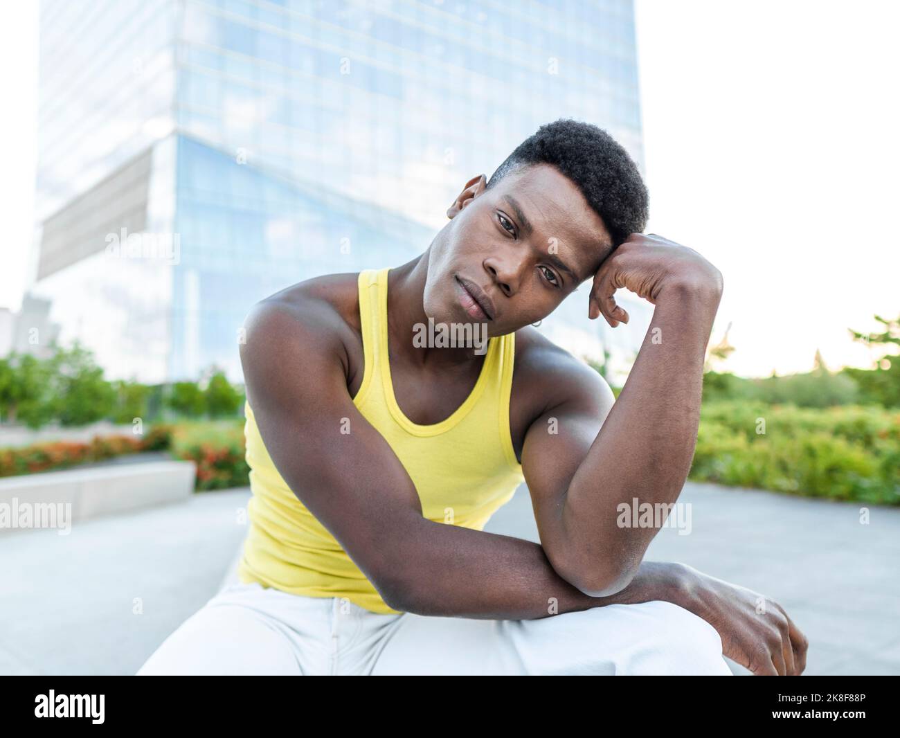 Jeune homme portant une veste jaune devant un bâtiment moderne Banque D'Images