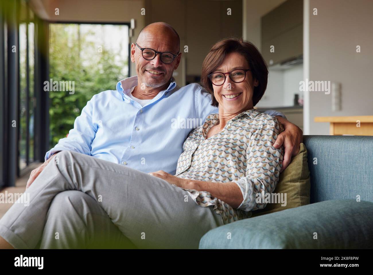 Heureux couple senior portant des lunettes de vue assis ensemble à la maison Banque D'Images