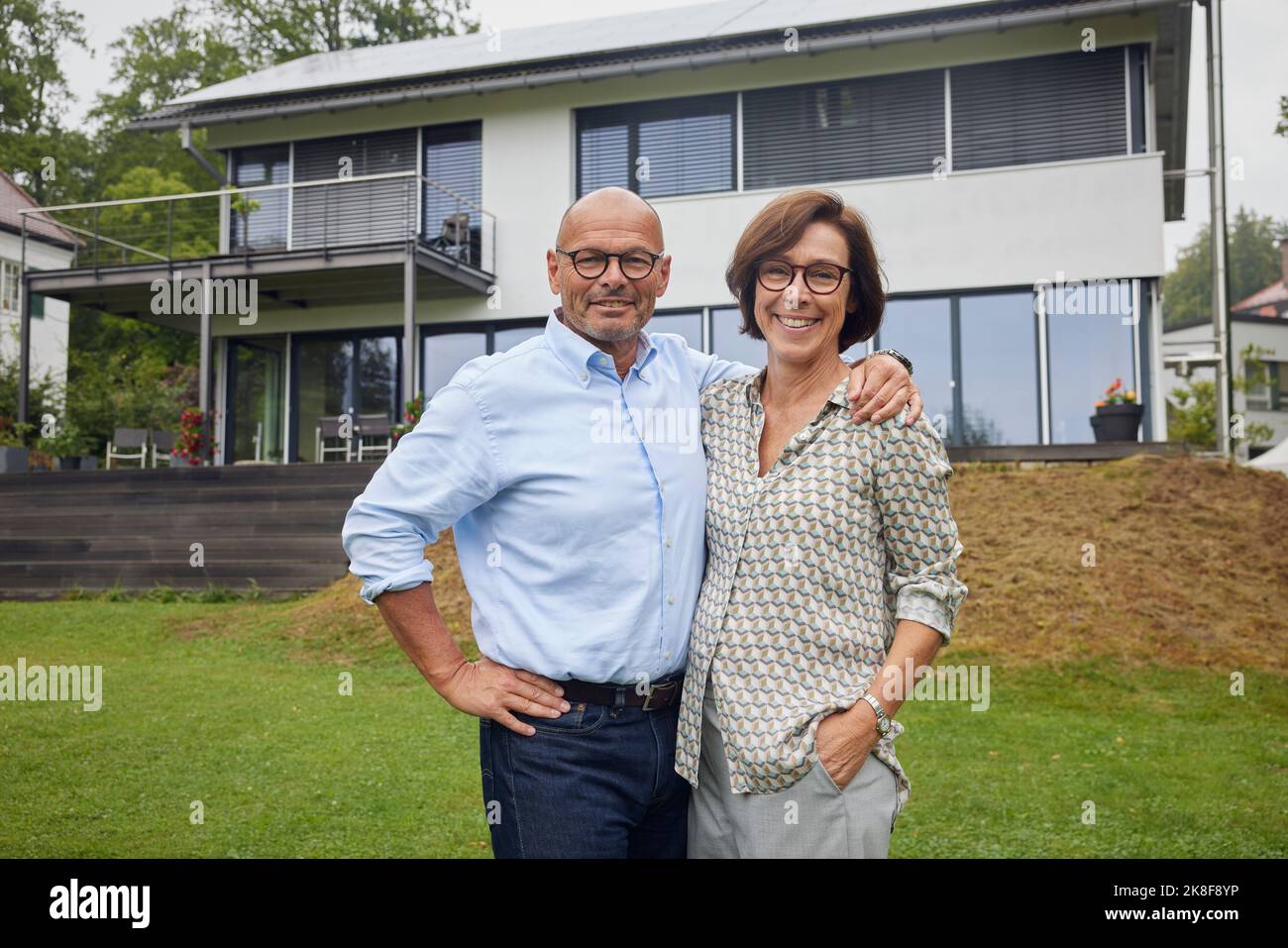 Heureux couple senior debout ensemble devant la maison Banque D'Images