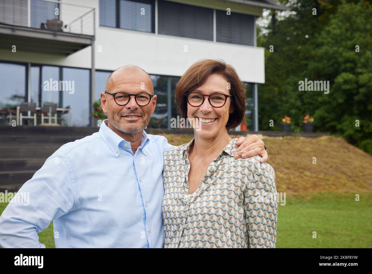 Couple senior aimant debout devant la maison Banque D'Images