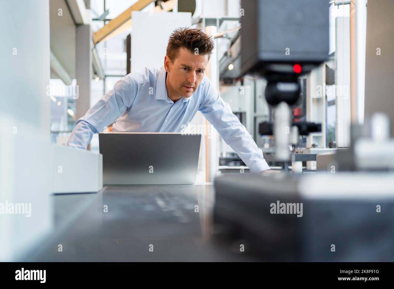 Technicien mature concentré travaillant en usine Banque D'Images
