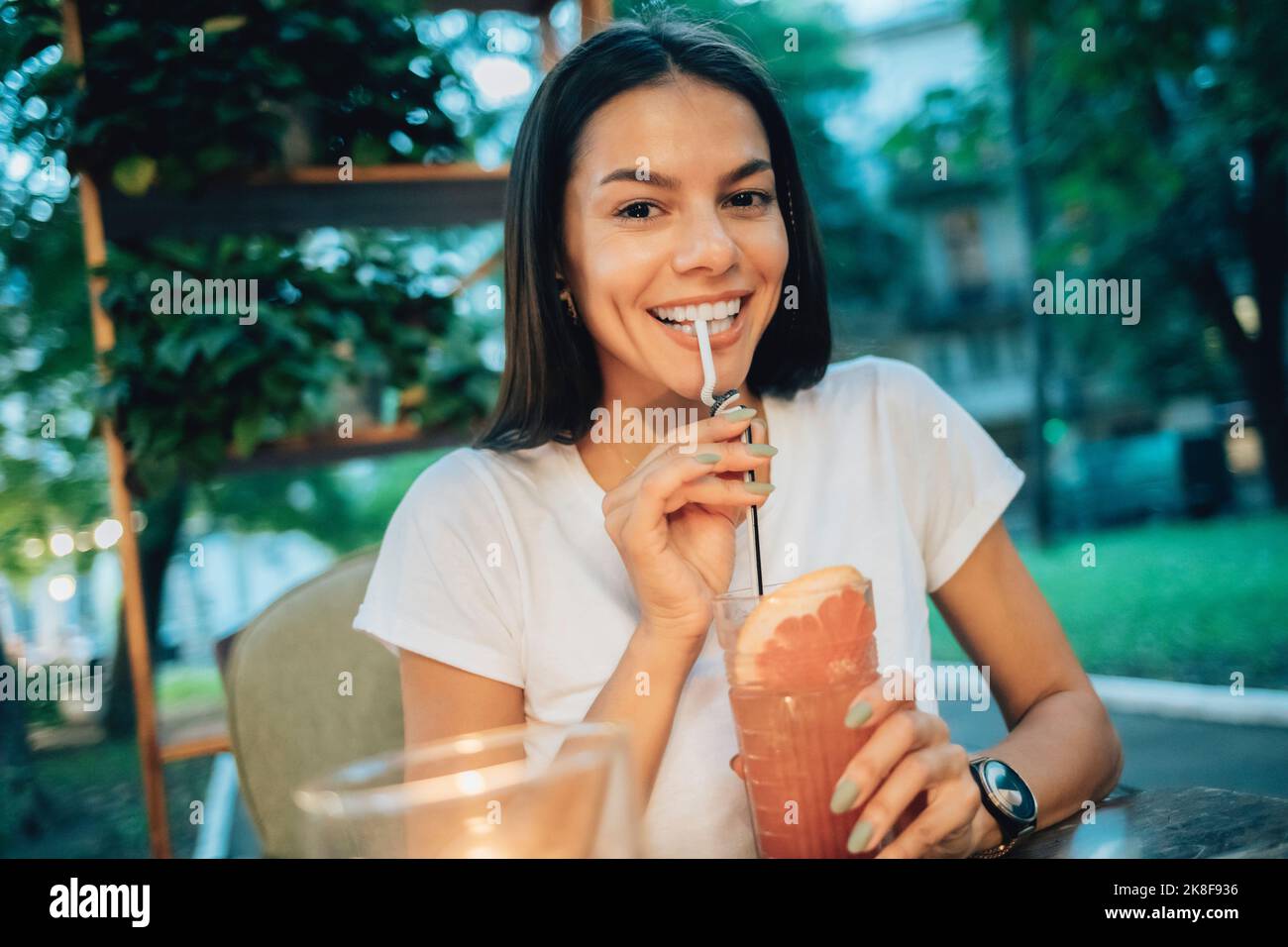 Bonne femme qui boit un cocktail au café-terrasse Banque D'Images
