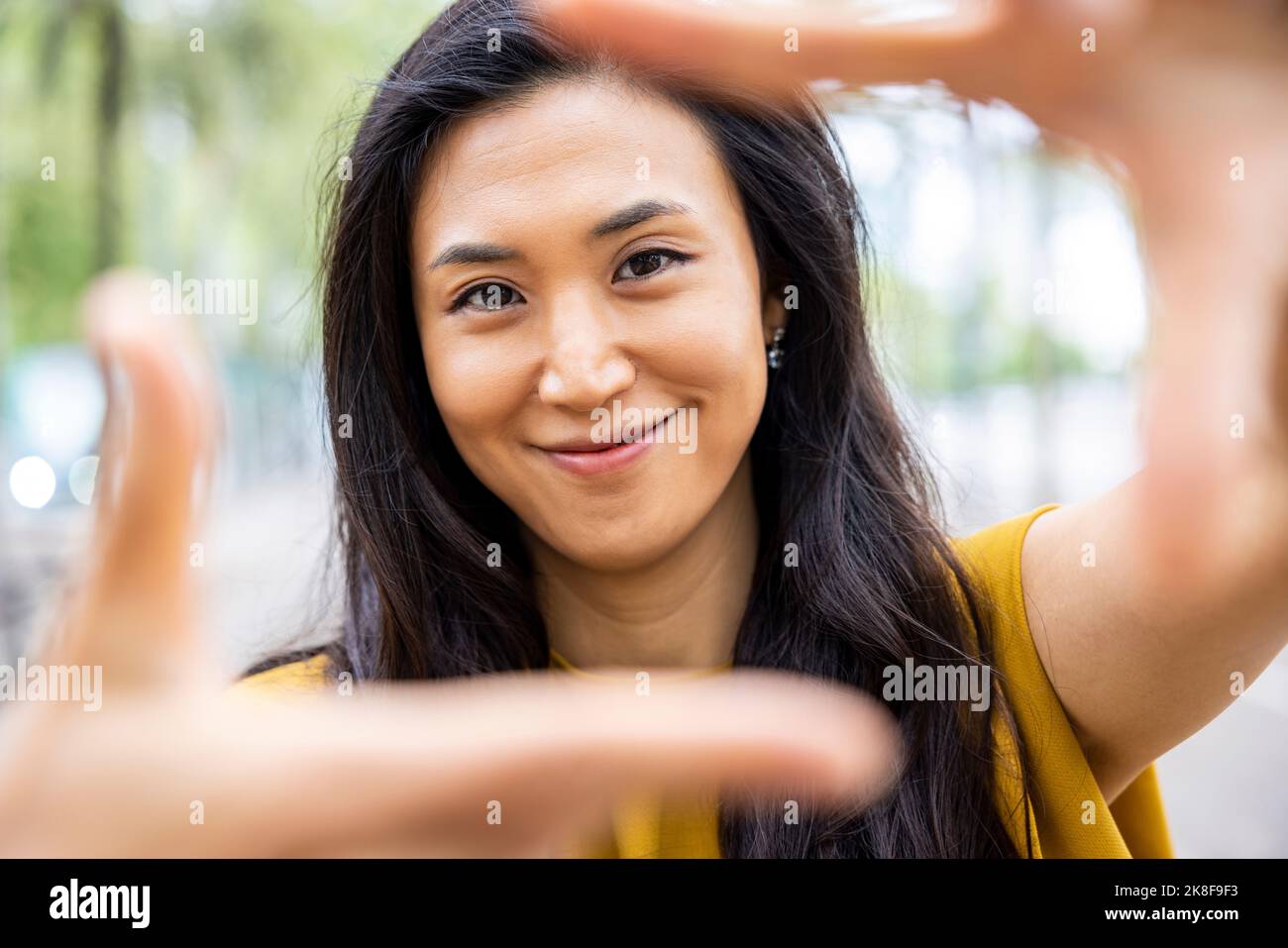 Femme souriante faisant le cadre du doigt Banque D'Images