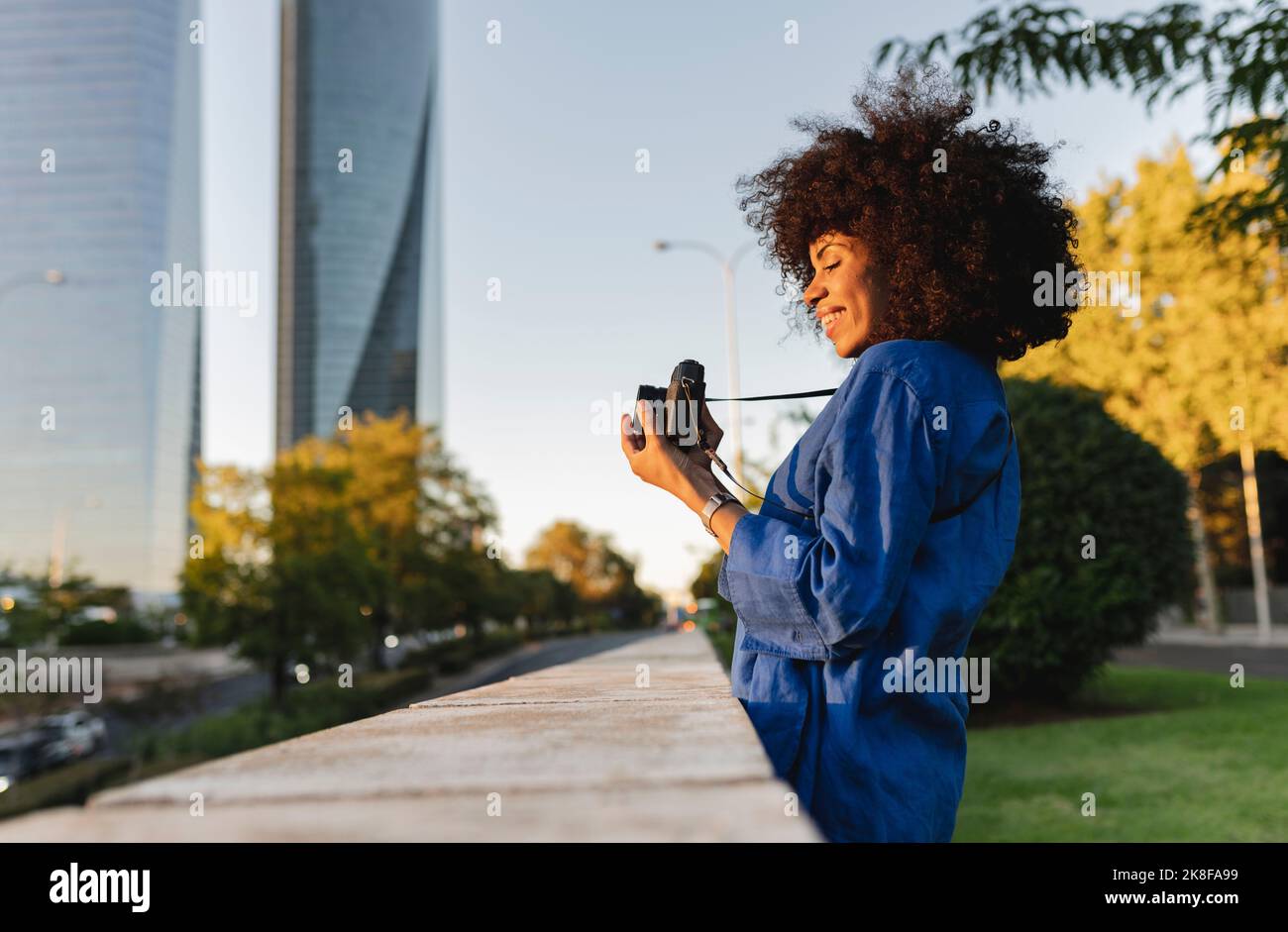 Femme souriante photographiant à travers l'appareil photo au mur Banque D'Images