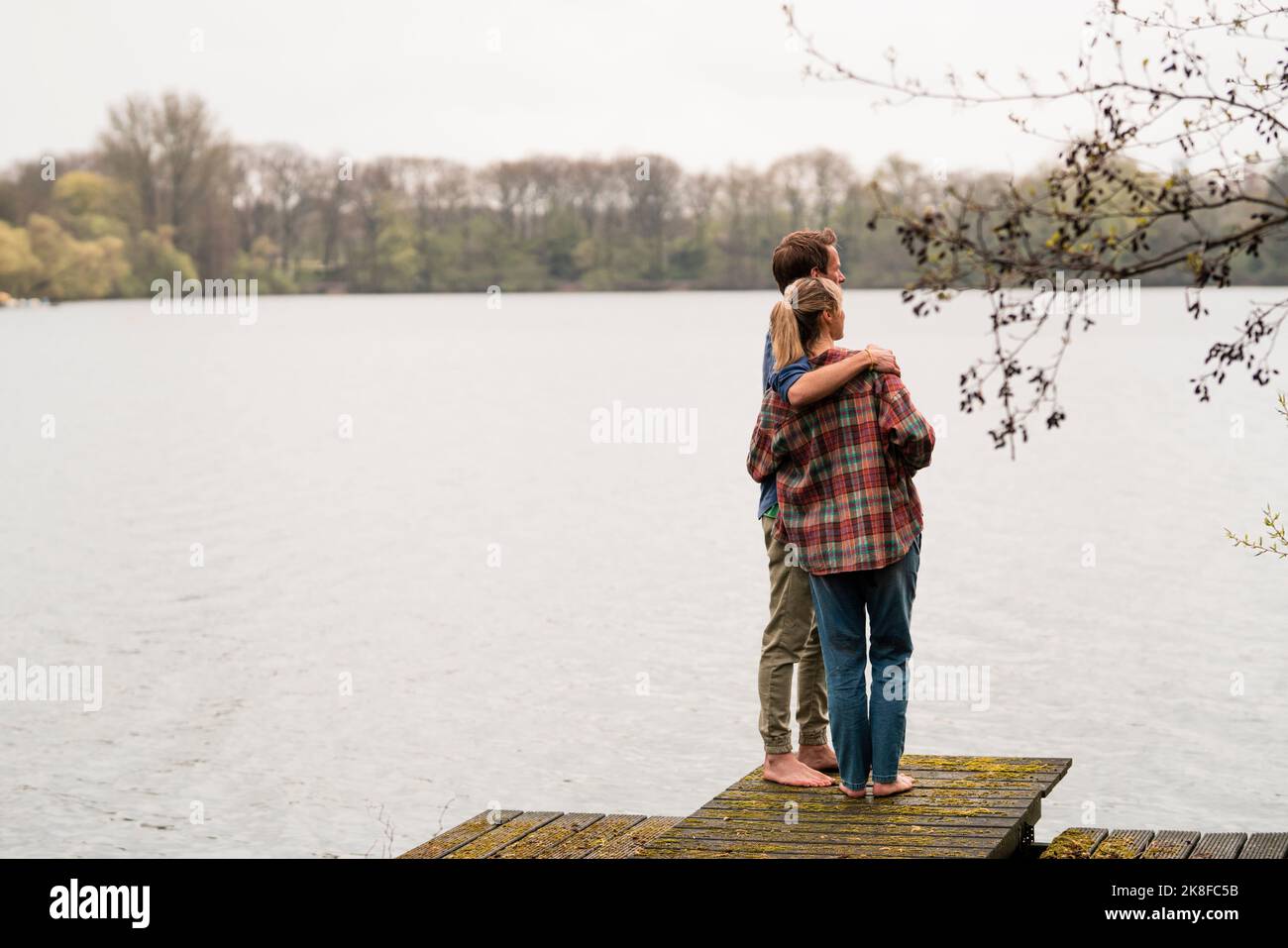 Homme avec le bras autour de la femme debout sur la jetée regardant le lac Banque D'Images