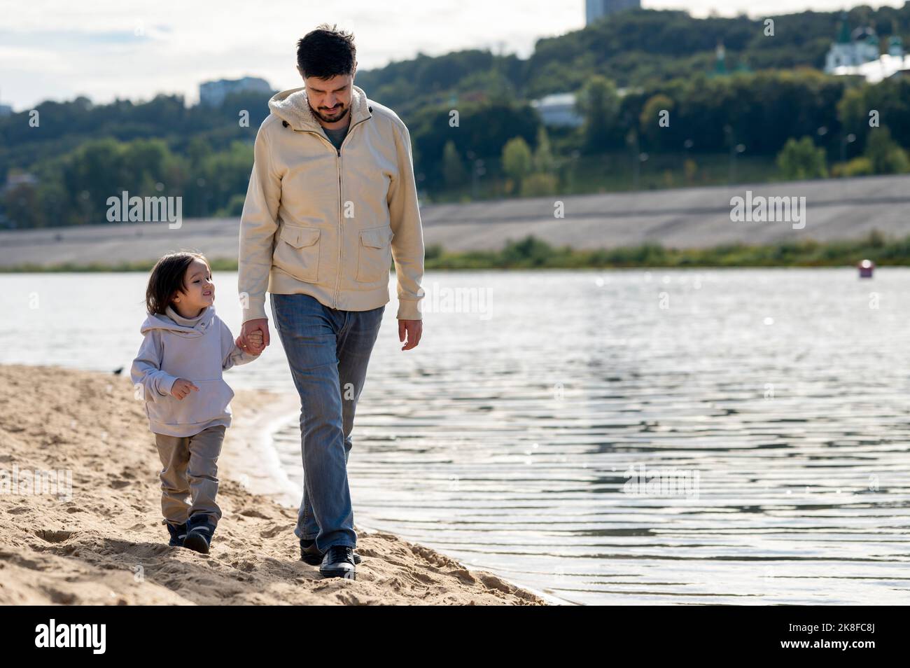Père et fils marchant ensemble en tenant les mains par la rivière Banque D'Images Père et fils marchant ensemble en tenant les mains par la rivière Banque D'Images