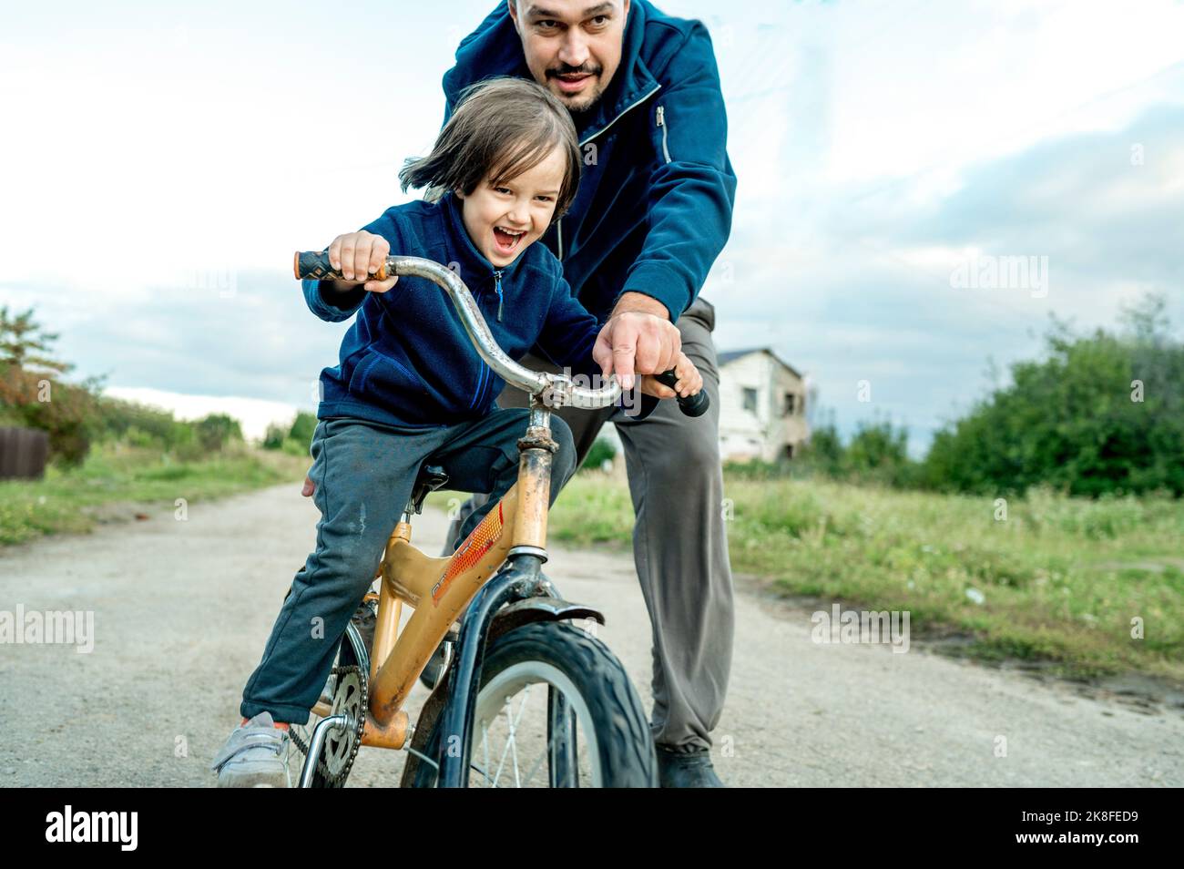 Homme aidant son à faire du vélo sur la route Banque D'Images