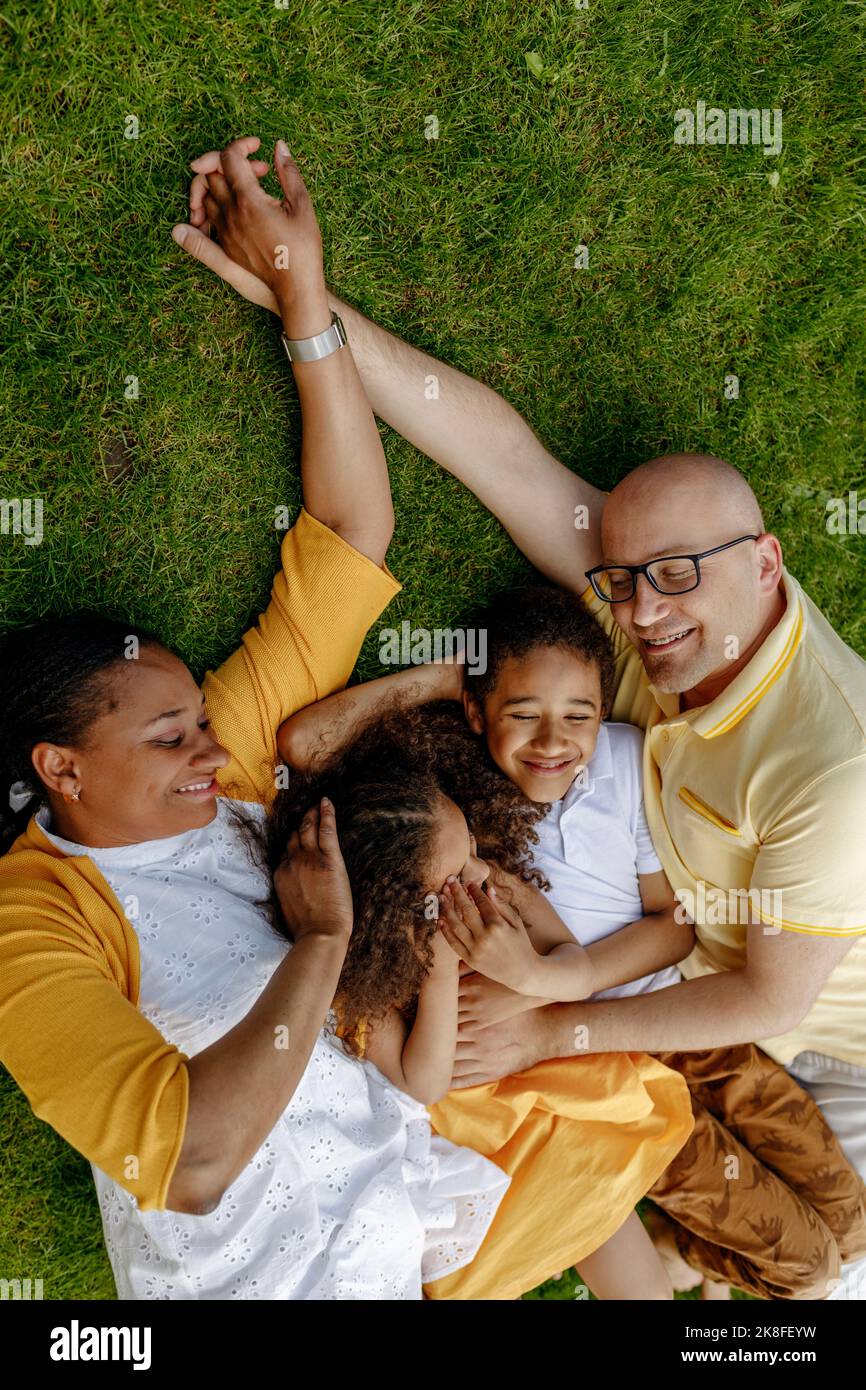 Parents souriants avec enfants allongé sur l'herbe Banque D'Images