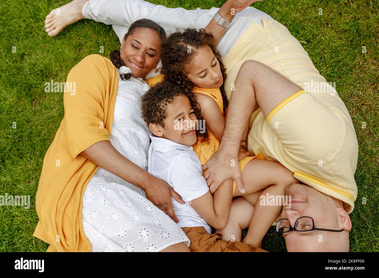 Parents souriants avec enfants allongé sur l'herbe Banque D'Images