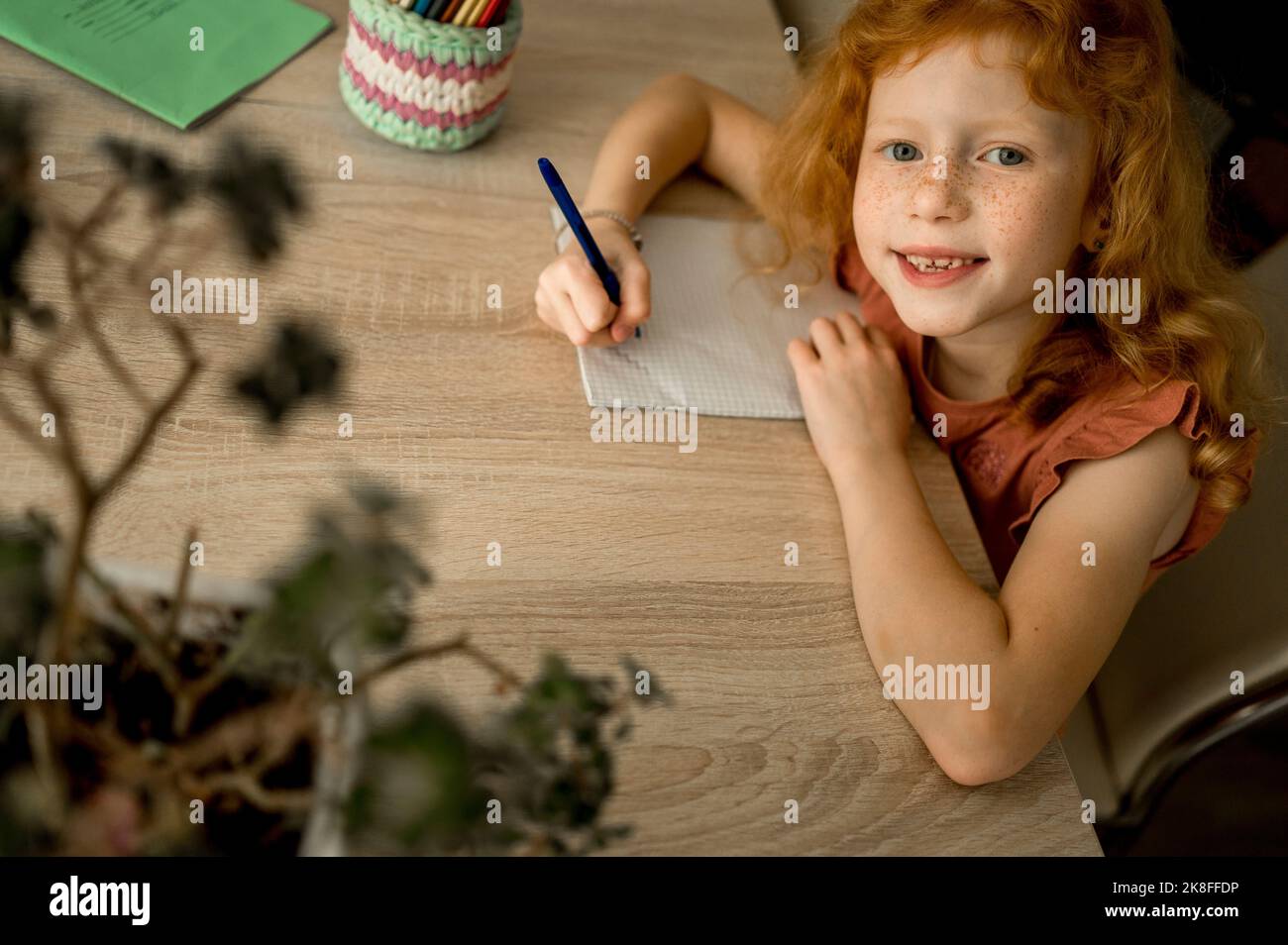 Sourire redhead fille dessin avec crayon de couleur à la maison Banque D'Images