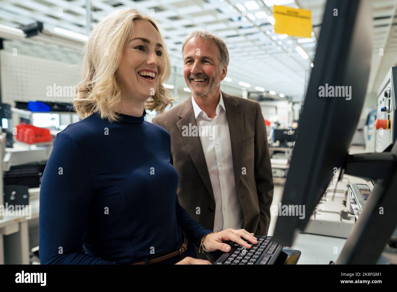 Bonne femme d'affaires utilisant l'ordinateur debout par un collègue de l'industrie Banque D'Images