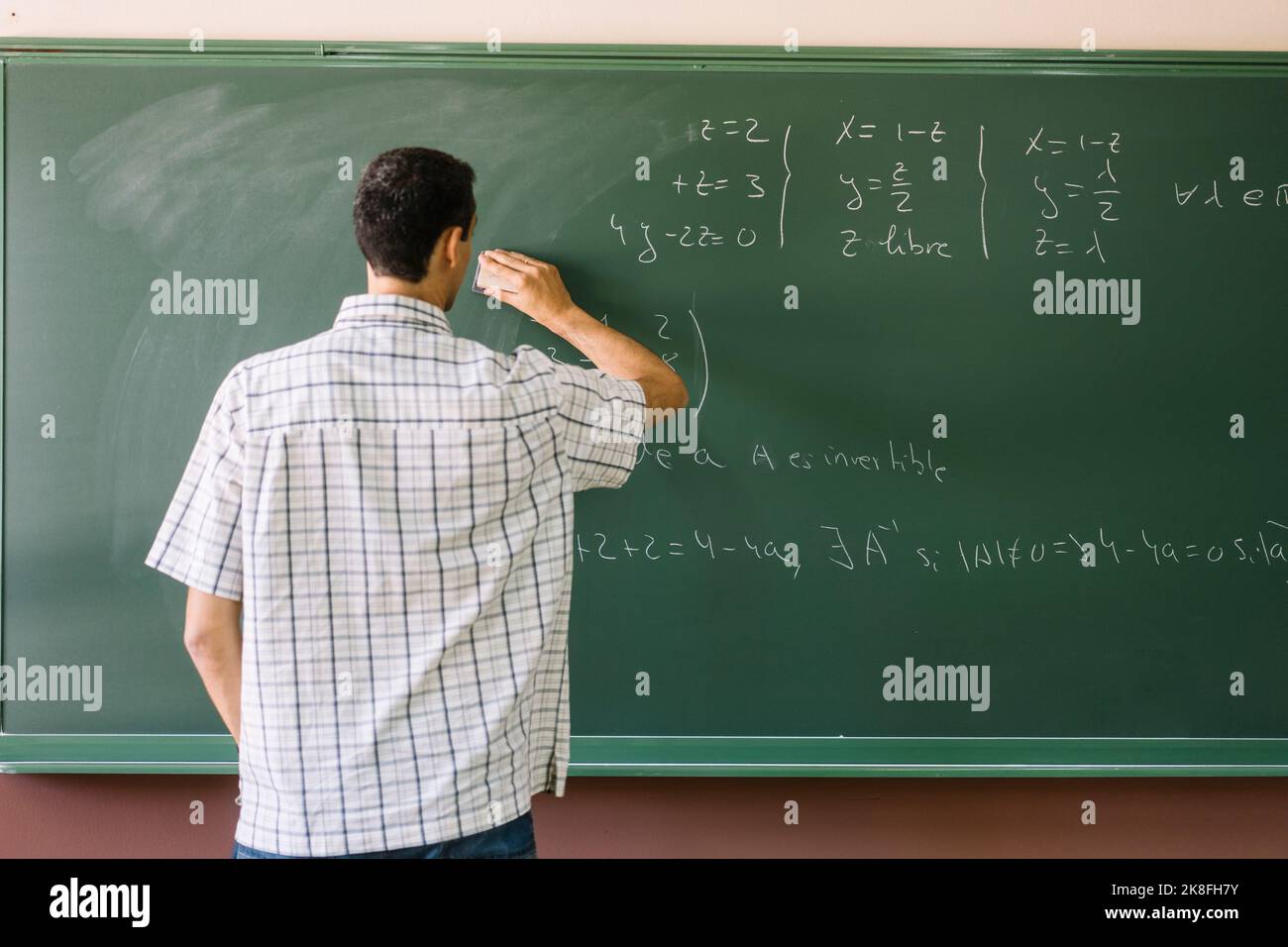 Professeur effaçant les formules mathématiques sur le tableau de surveillance Banque D'Images