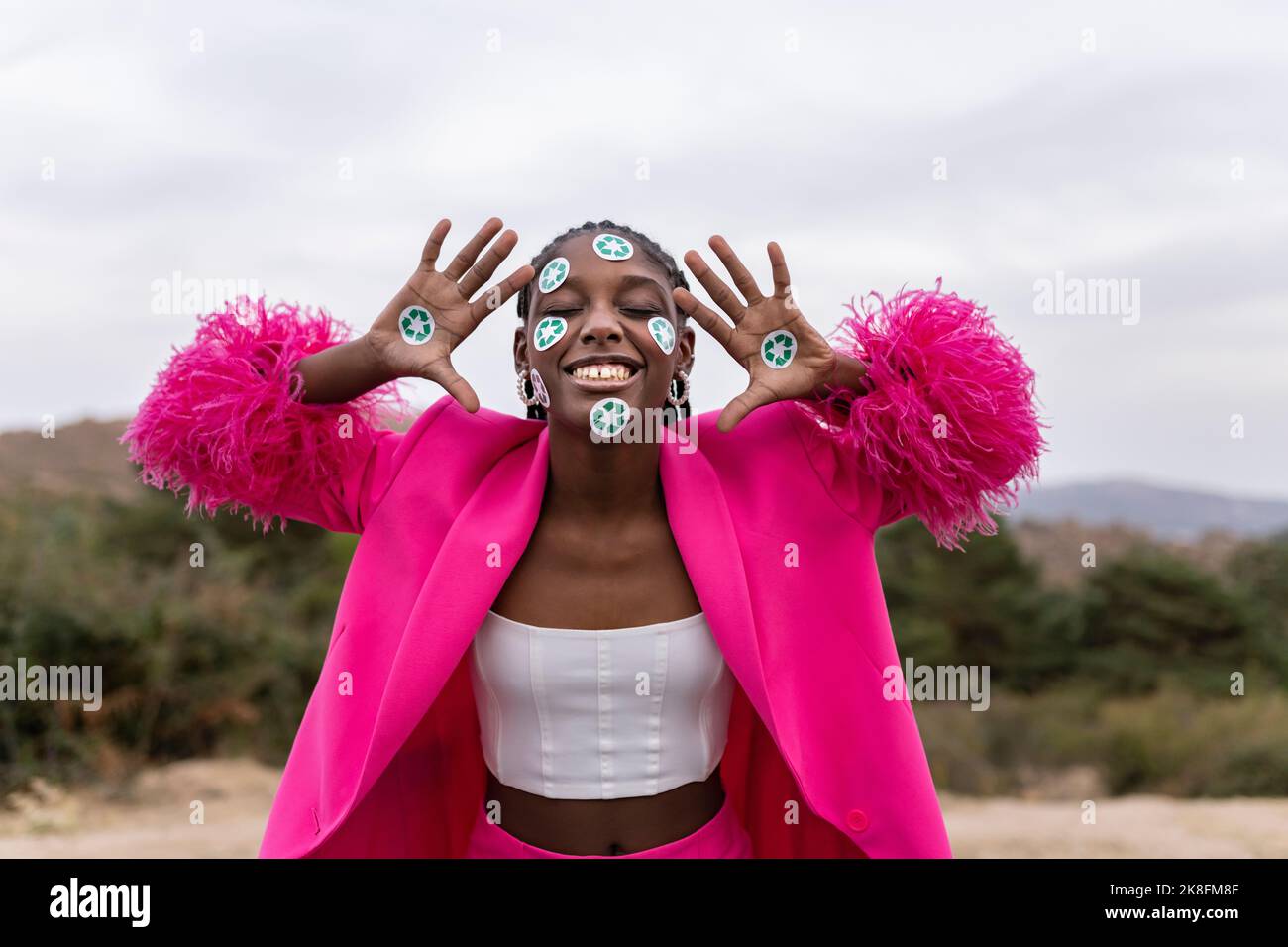 Femme joyeuse avec autocollants de symbole de recyclage sur le visage et la main Banque D'Images