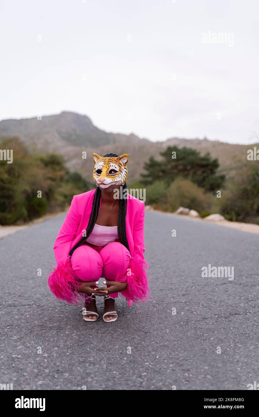 Jeune femme portant un masque tigre qui croque sur la route Banque D'Images