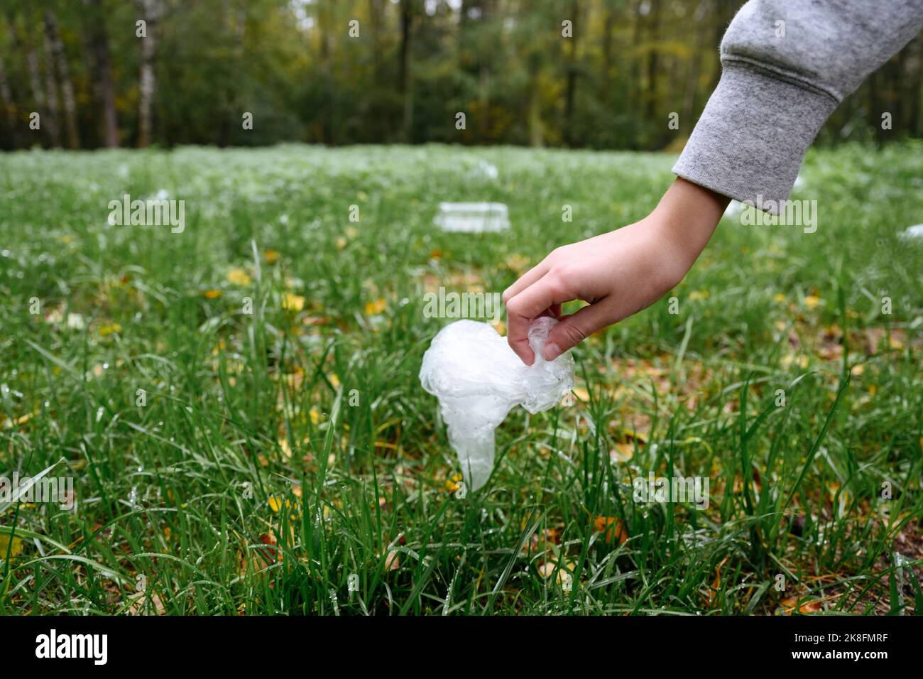Main du garçon ramassant le plastique de l'herbe Banque D'Images
