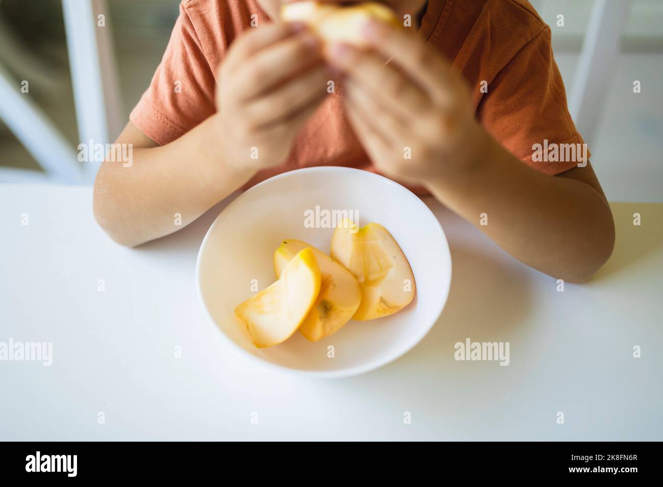 Tranches de pomme dans un bol sur la table par garçon à la maison Banque D'Images