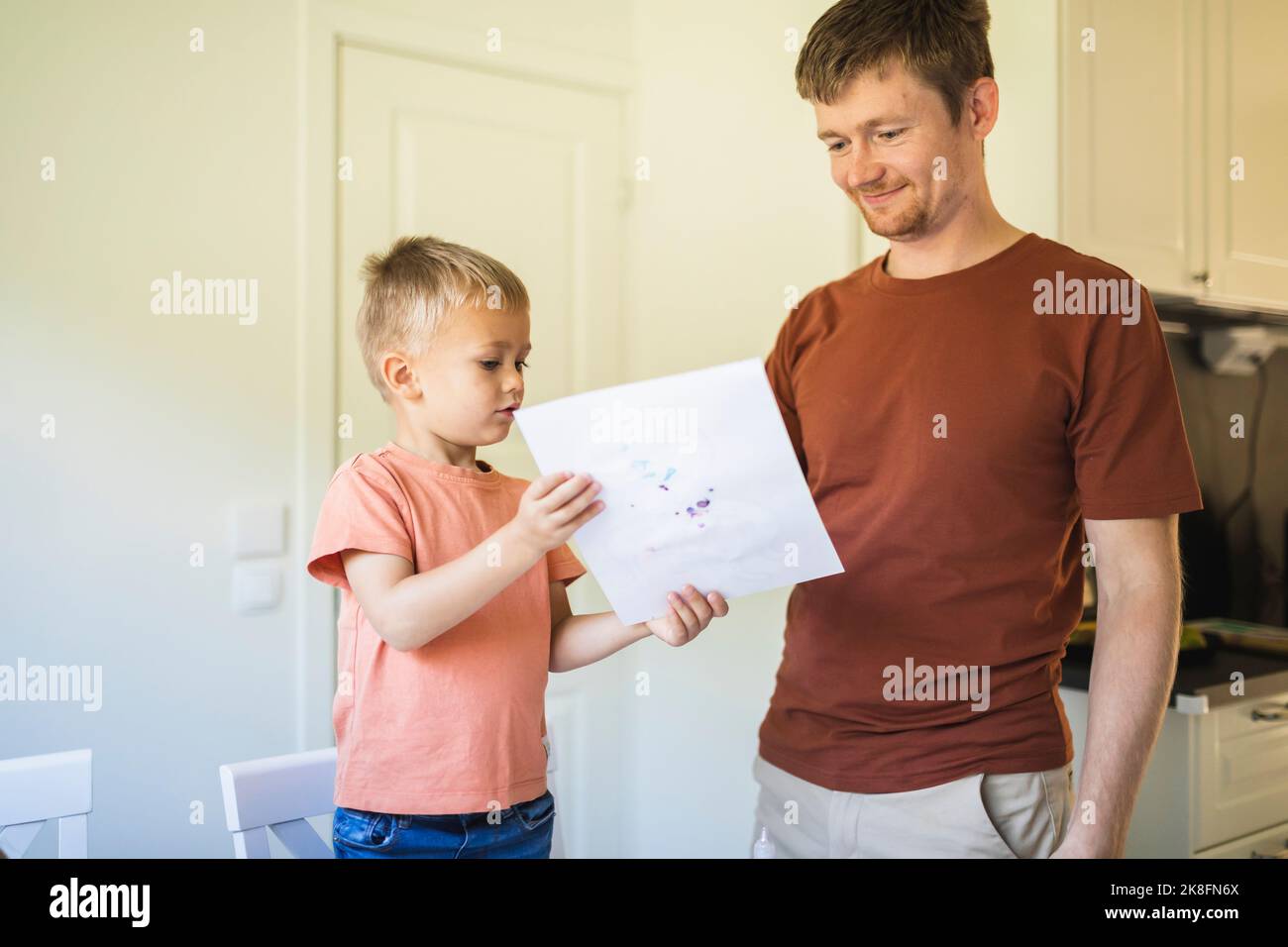 Fils montrant le dessin au père à la maison Banque D'Images