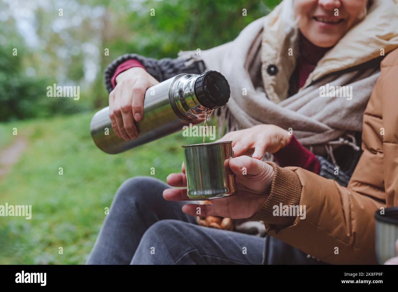 Femme versant de l'eau de thermos par l'homme dans la forêt Banque D'Images