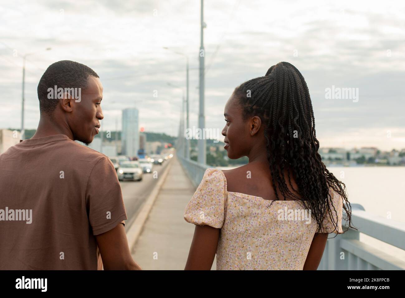 Un jeune couple marche ensemble sur le pont au coucher du soleil Banque D'Images Un jeune couple marche ensemble sur le pont au coucher du soleil Banque D'Images