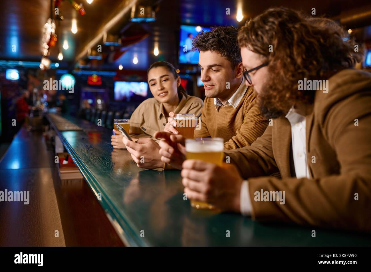 Les amis se reposent dans le bar sportif, se concentrent sur les jeunes hommes qui boivent de la bière Banque D'Images