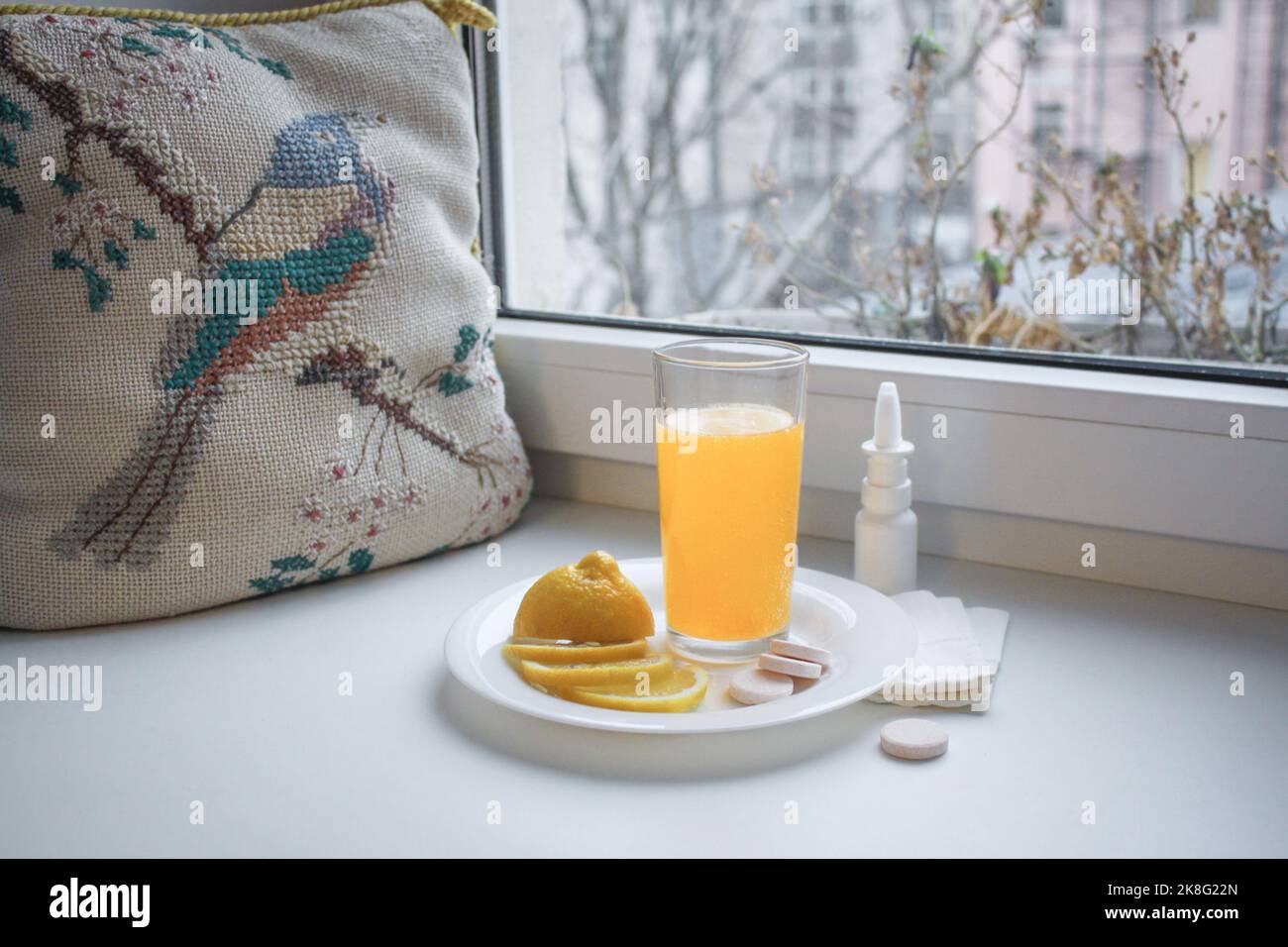 Froid de saison : verre avec vitamine C liquide, citron en tranches, pilules instantanées et vaporisateur nasal avec serviettes en papier sur le rebord de la fenêtre. À côté de la vintage Banque D'Images