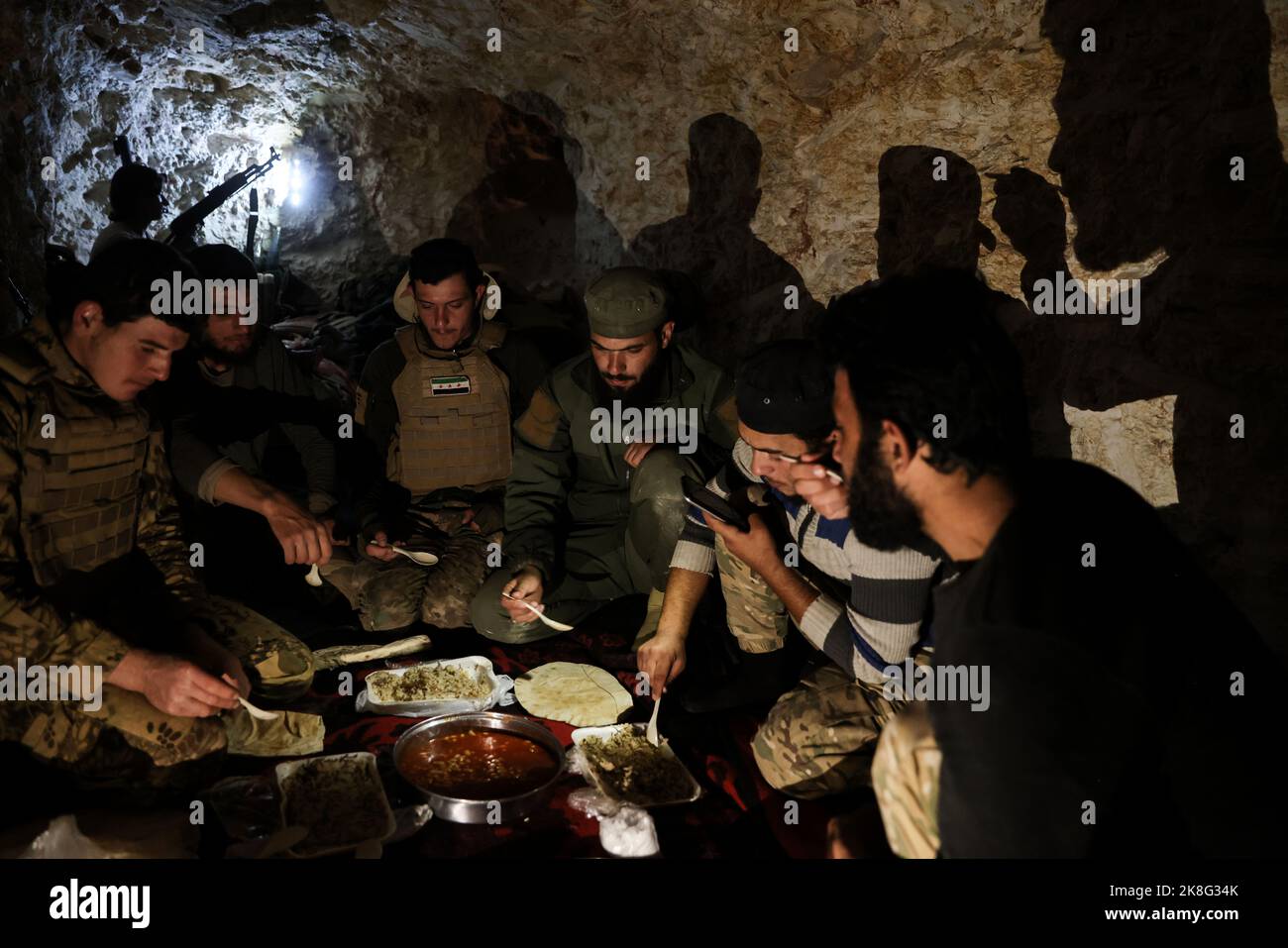 Idlib, Syrie. 23rd octobre 2022. Les combattants de l'opposition syrienne armée, connue sous le nom de Front de libération nationale (NFL), se nourrissent ensemble dans un tunnel souterrain sur les lignes de front face aux forces du régime syrien, dans la campagne d'Idlib. Credit: Aras Alkharboutli/dpa/Alamy Live News Banque D'Images