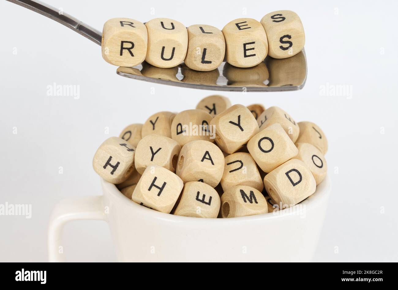 Concept d'entreprise. Les cubes avec l'image des lettres sont versés dans la tasse, au-dessus de la tasse il y a une cuillère avec des cubes avec l'inscription - règles Banque D'Images