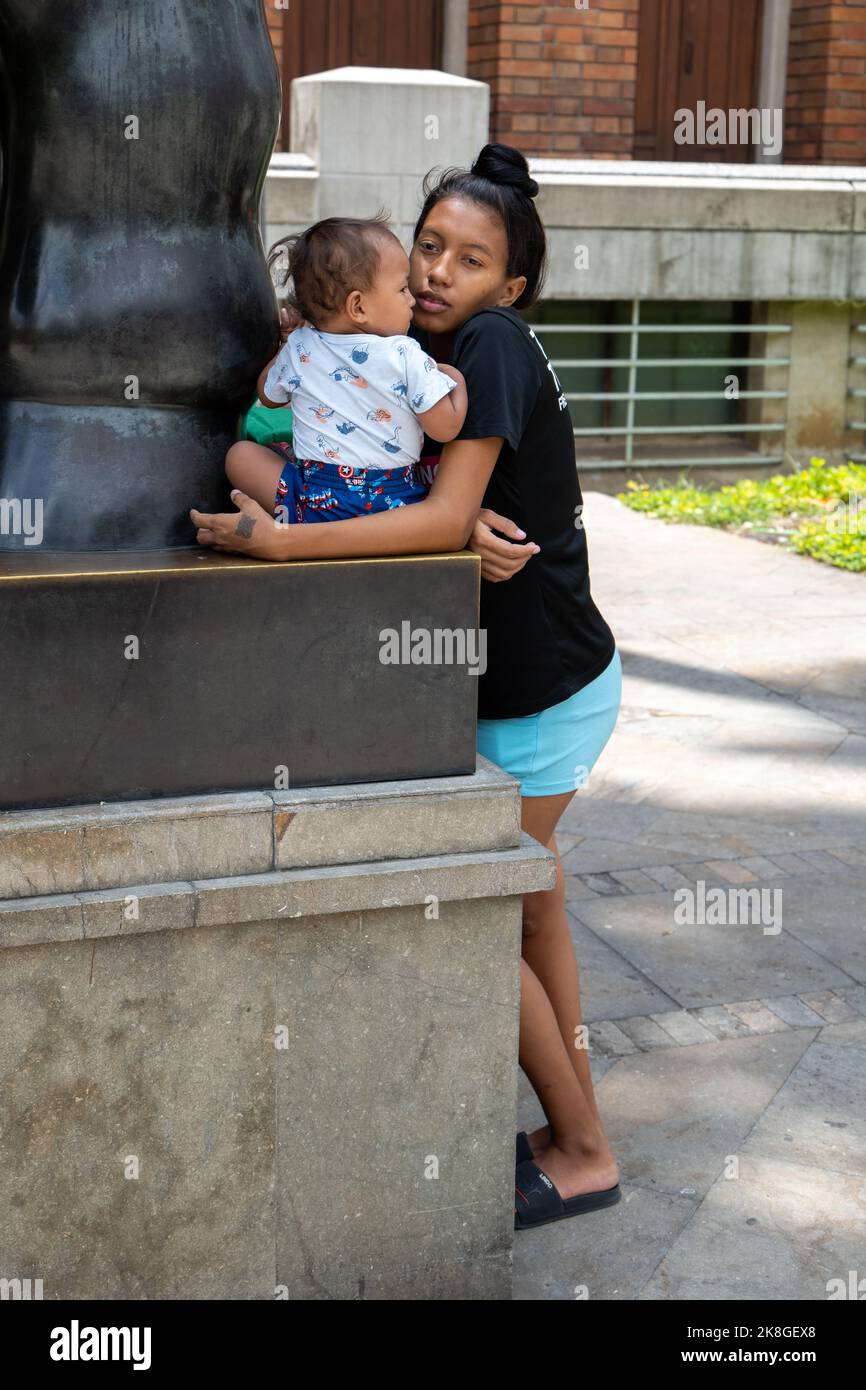 Medellin, Antioquia, Colombie - 12 septembre 2022: Jeune coiffeuse noire tient un bébé sur une sculpture de bronze, la statue d'une grande femme caractère b Banque D'Images