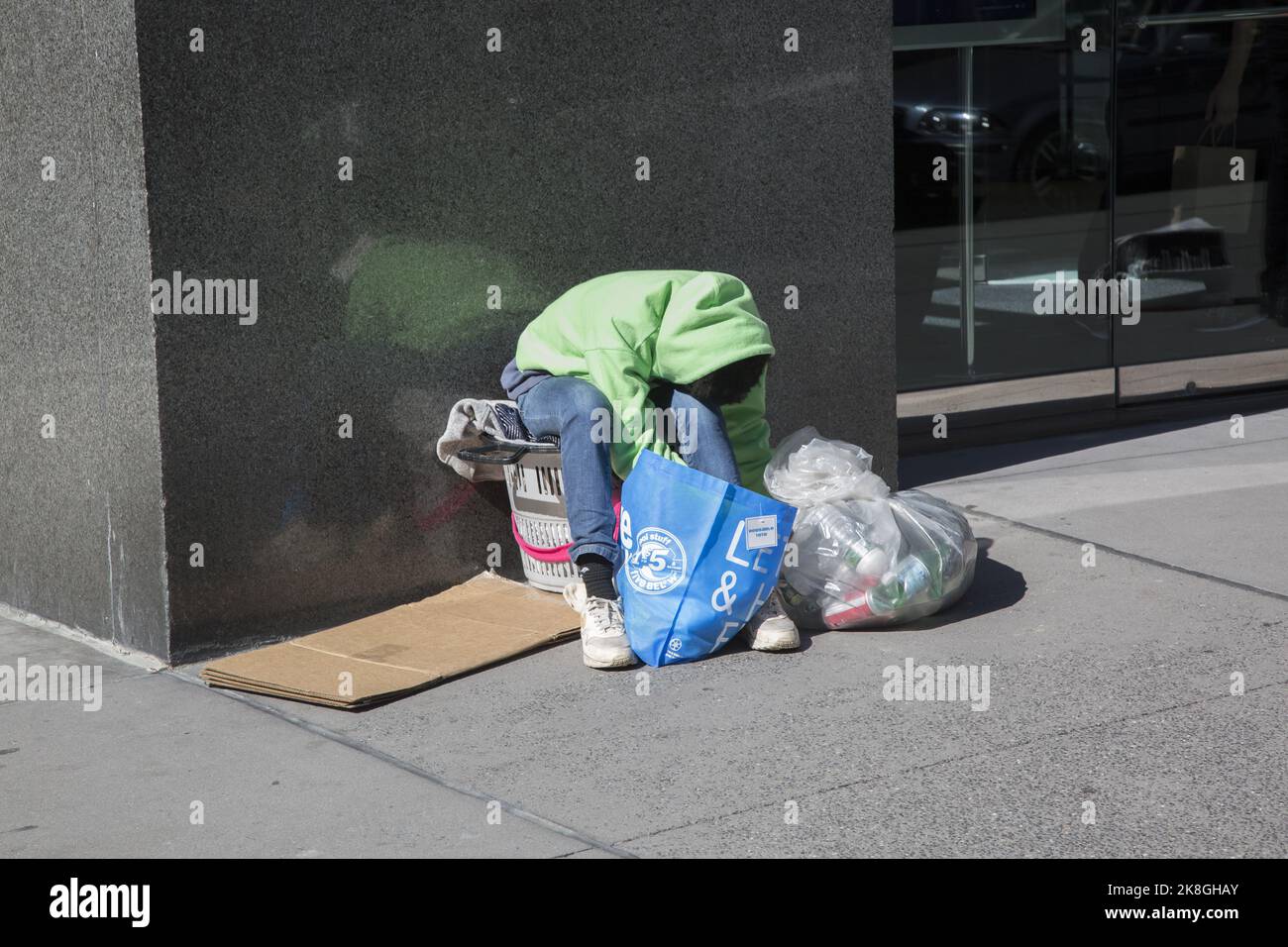 Homme sans abri avec un sac de bouteilles avec la valeur de dépôt sur eux pour gratter quelques dollars. Reposant sur un trottoir dans le centre de Manhattan, New York Banque D'Images