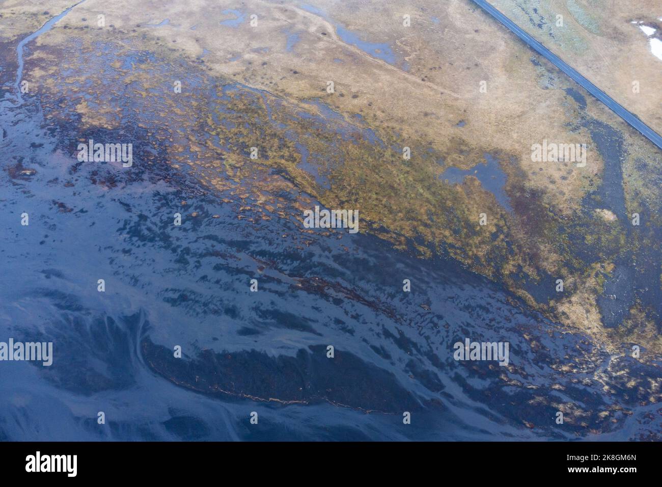 De dessus la route d'asphalte droite traversant la zone humide par temps froid d'hiver dans la campagne de l'Islande Banque D'Images