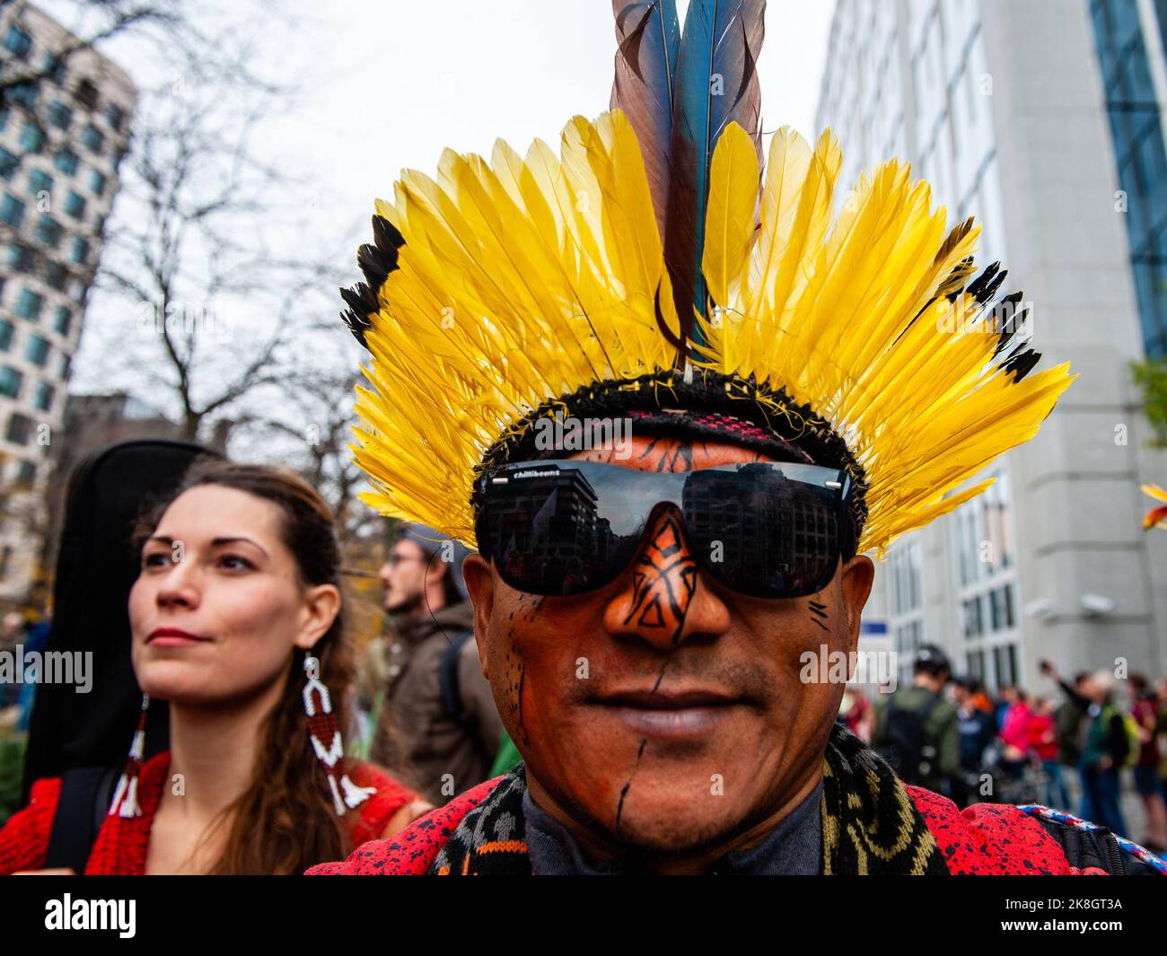 Un autochtone est vu porter de la peinture traditionnelle sur son visage  avec des plumes jaunes et des lunettes de soleil pendant la marche  climatique. Des milliers de personnes se sont rassemblées