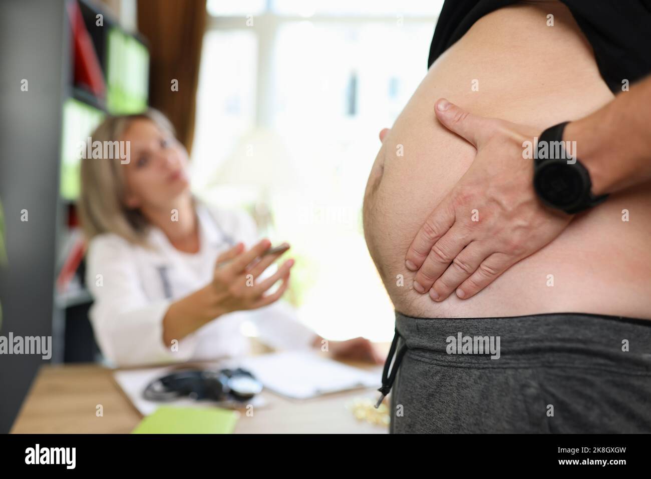 Homme touchant et montrant le ventre gras au médecin nutritionniste Banque D'Images