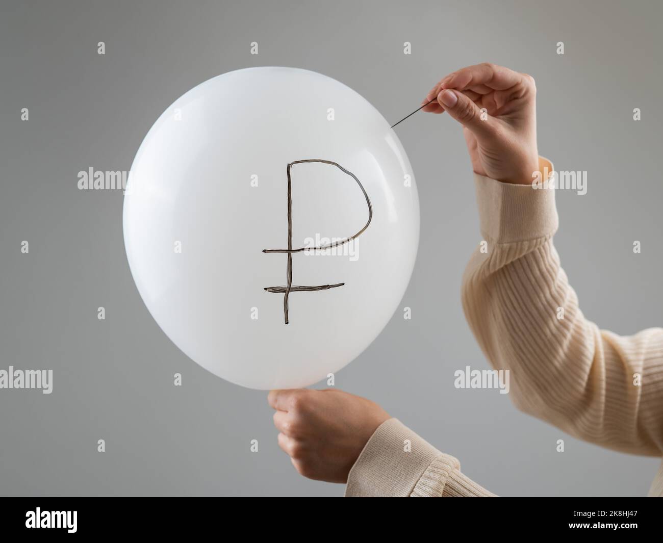Une femme caucasienne fait apparaître un ballon avec une inscription rouble et une aiguille. Banque D'Images