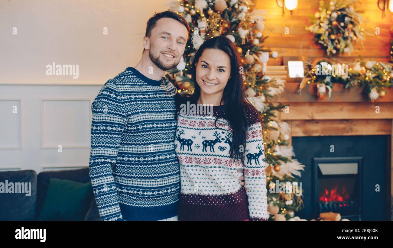 Portrait d'un couple heureux homme et femme debout ensemble le soir de Noël souriant et regardant l'appareil photo, les gens portent des chandails chauds. Banque D'Images