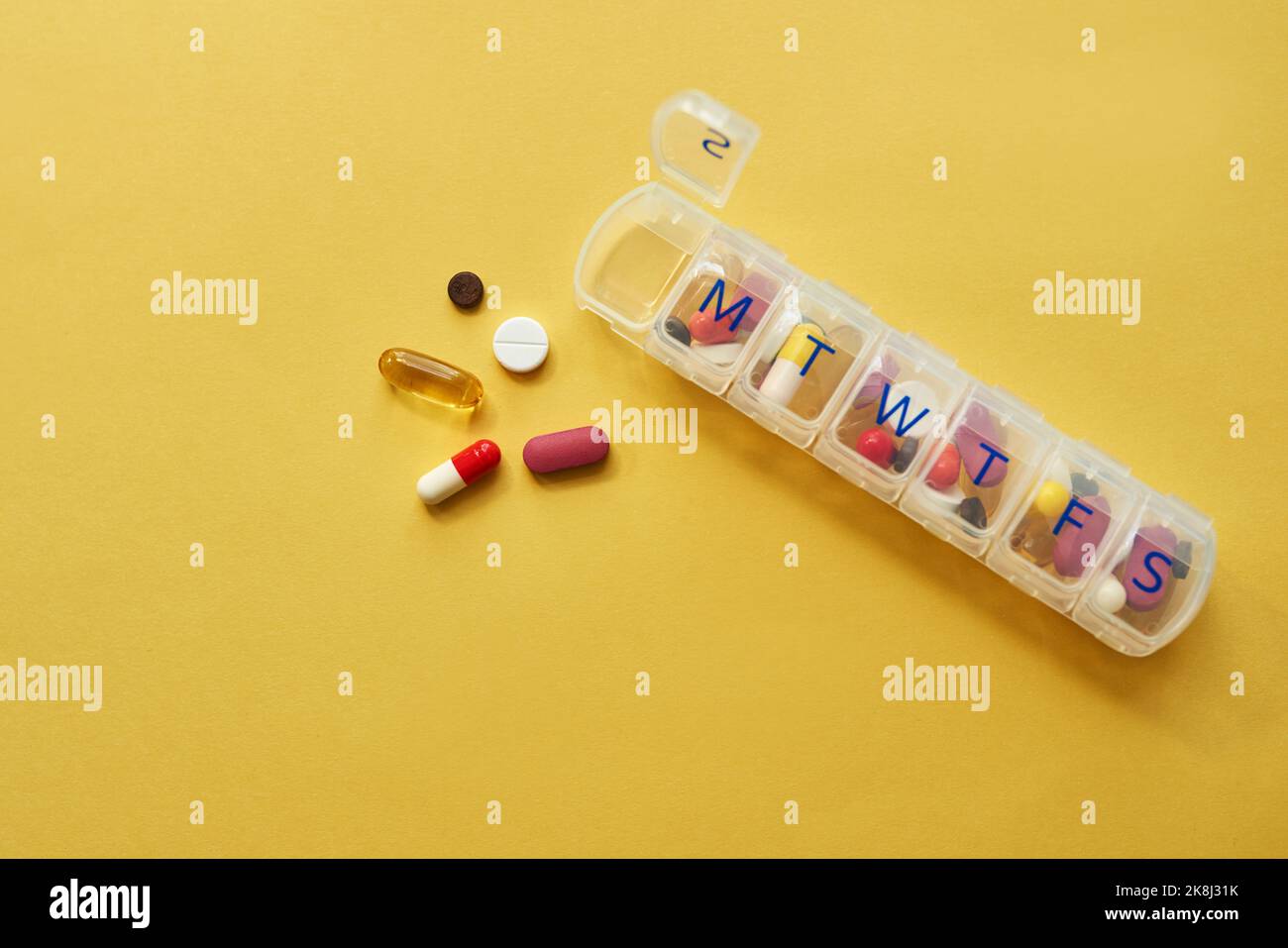 Le bon dosage fait une grande différence. Studio shot de comprimés dans un coffret de médicaments sur fond jaune. Banque D'Images