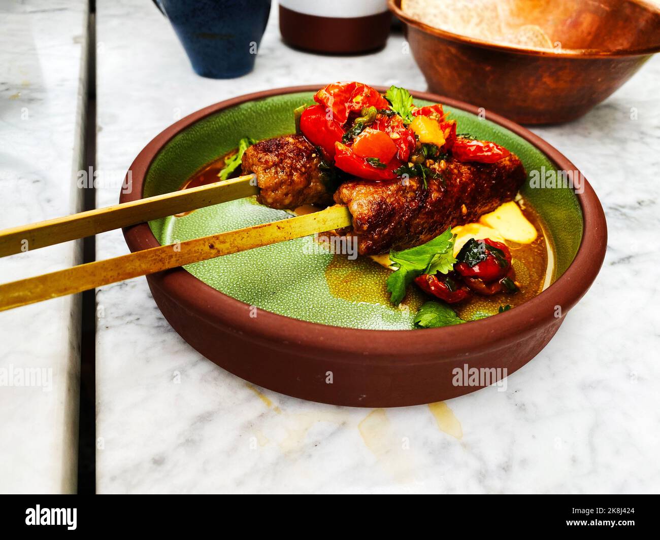 Kebabs sur brochettes. Kebabs de poulet dans un bol vert et brun dans un restaurant chic. Banque D'Images