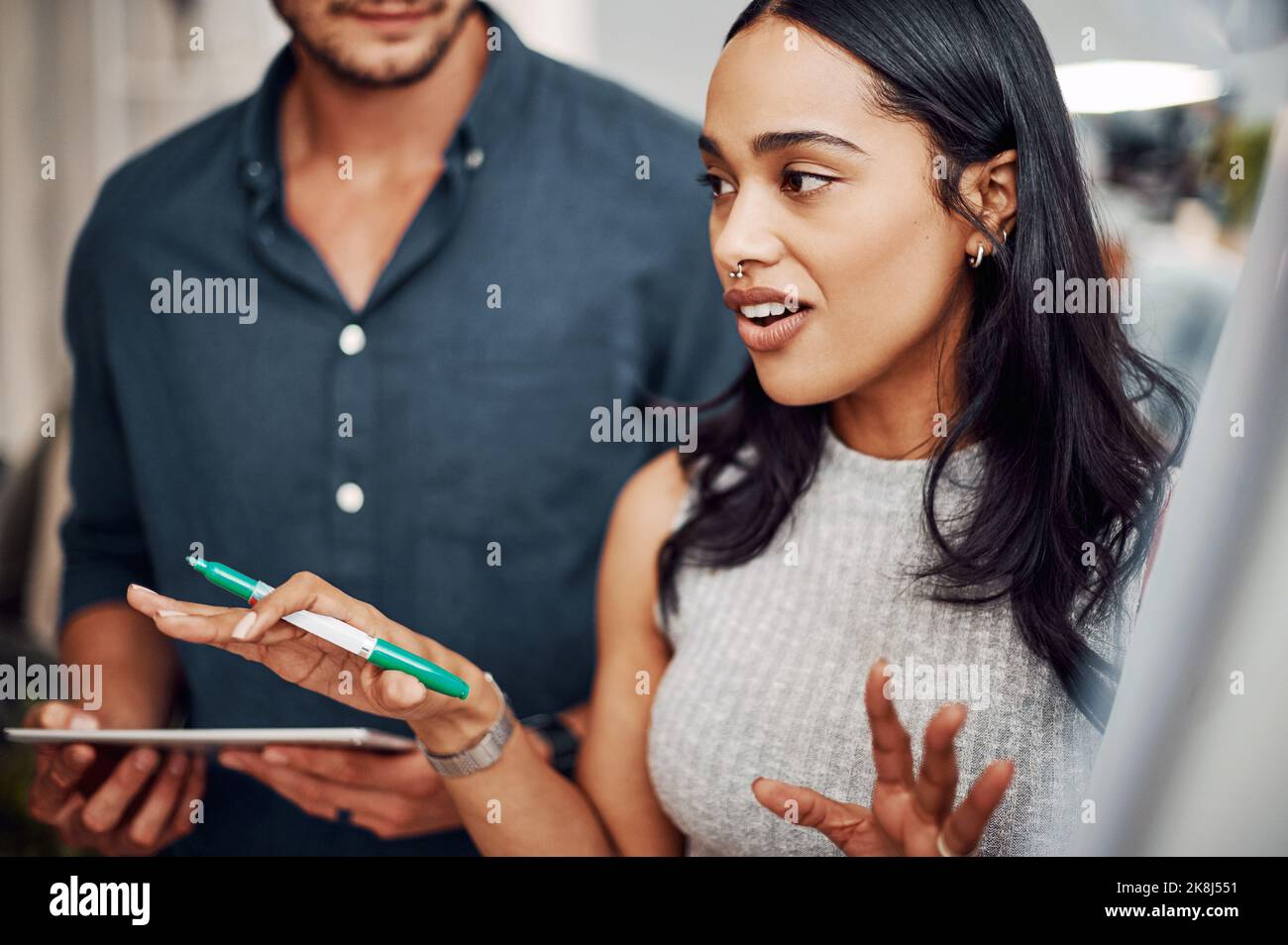 Expliquant son point de vue. Une jeune femme d'affaires attirante utilisant une aide visuelle pour réfléchir avec ses collègues au bureau. Banque D'Images
