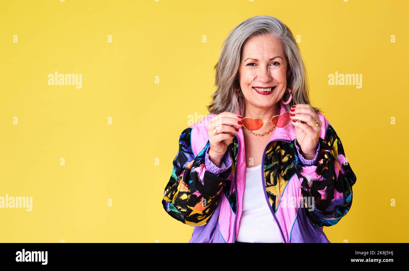 Vous êtes aussi vieux que vous le sentez. Portrait d'une femme âgée confiante et élégante posant sur un fond jaune. Banque D'Images