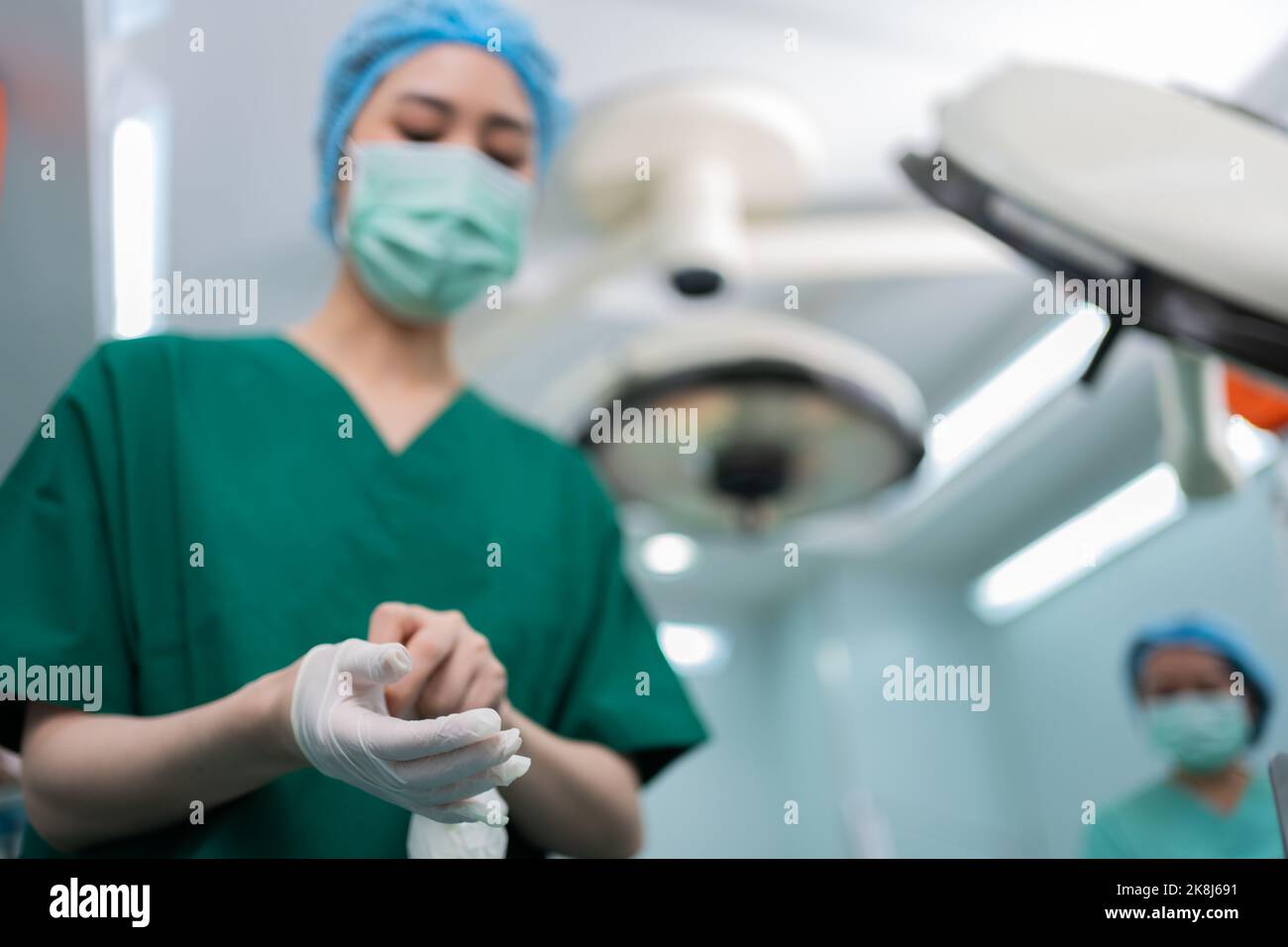Portrait d'un chirurgien asiatique avec un masque médical debout et portant des gants médicaux dans une salle d'opération à l'hôpital. Équipe de chirurgiens professionnels. Hé Banque D'Images