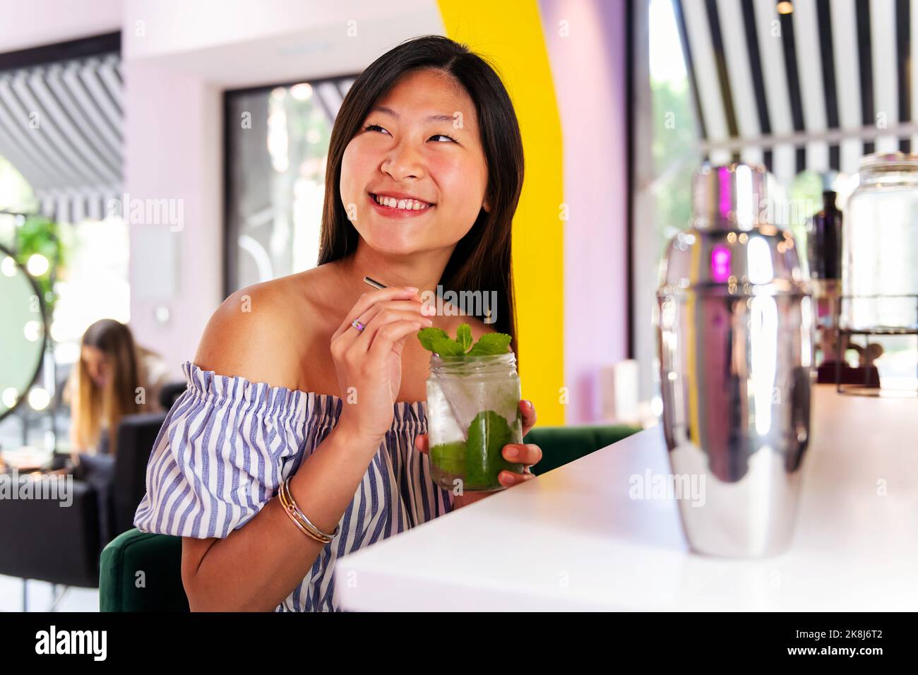 une femme souriante se réjouit de boire un soda Banque D'Images