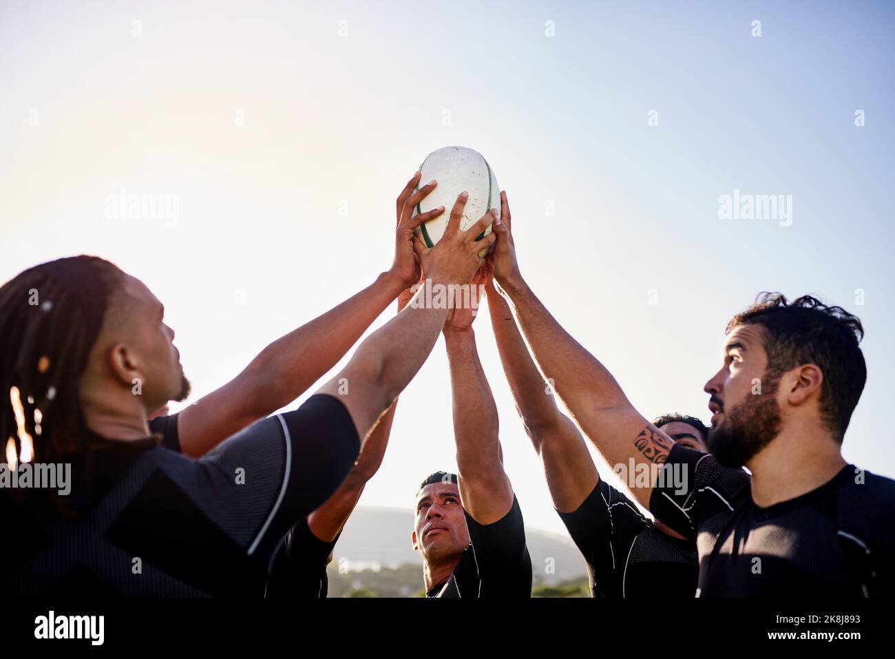 Le pouvoir est entre nos mains. Un groupe de sportifs séduisant tenant un ballon de rugby ensemble avant de jouer au rugby. Banque D'Images