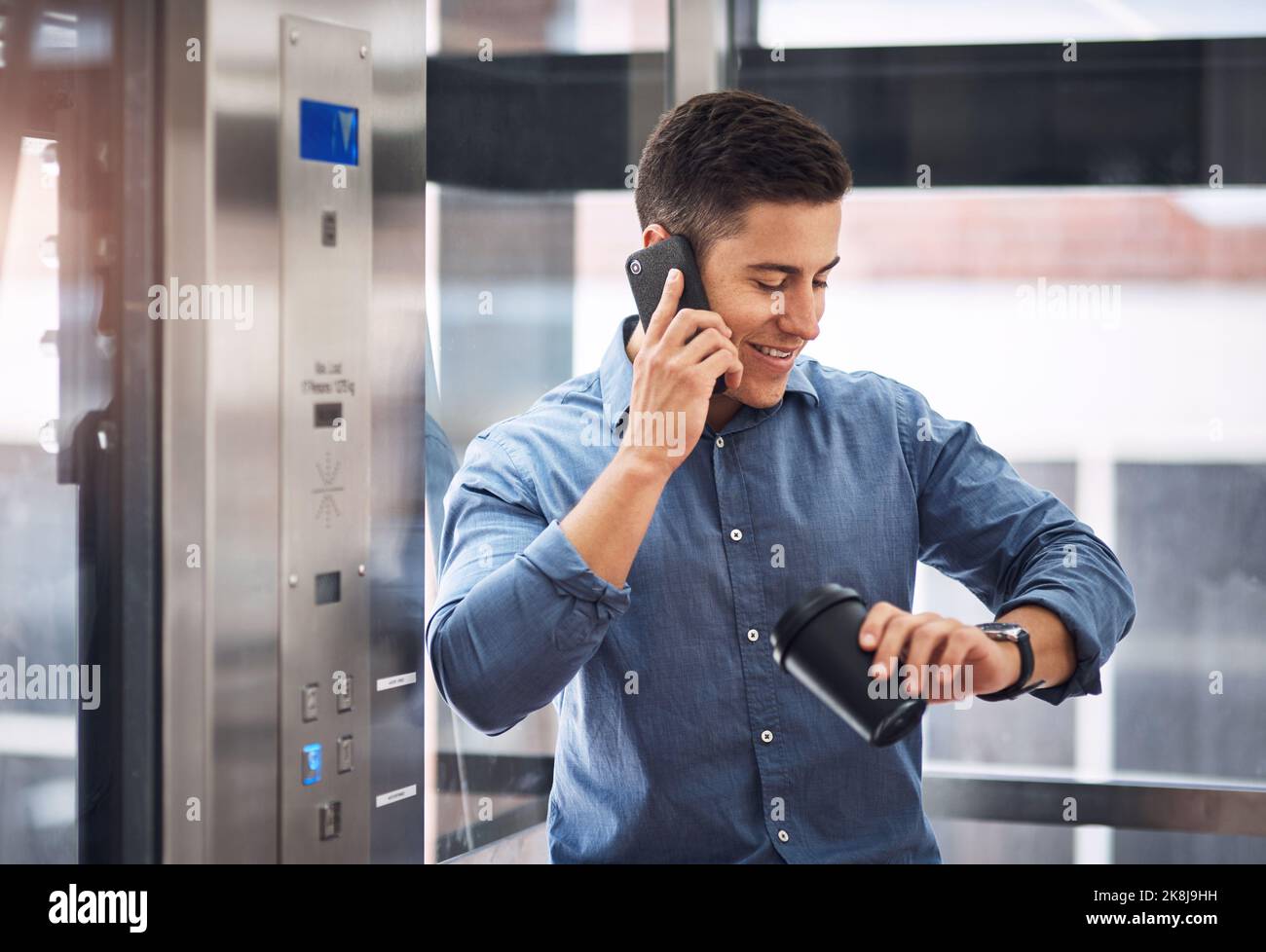 Je n'y trouve pas de temps à autre un jeune homme d'affaires qui parle sur un téléphone portable et vérifie sa montre en se tenant dans un ascenseur. Banque D'Images