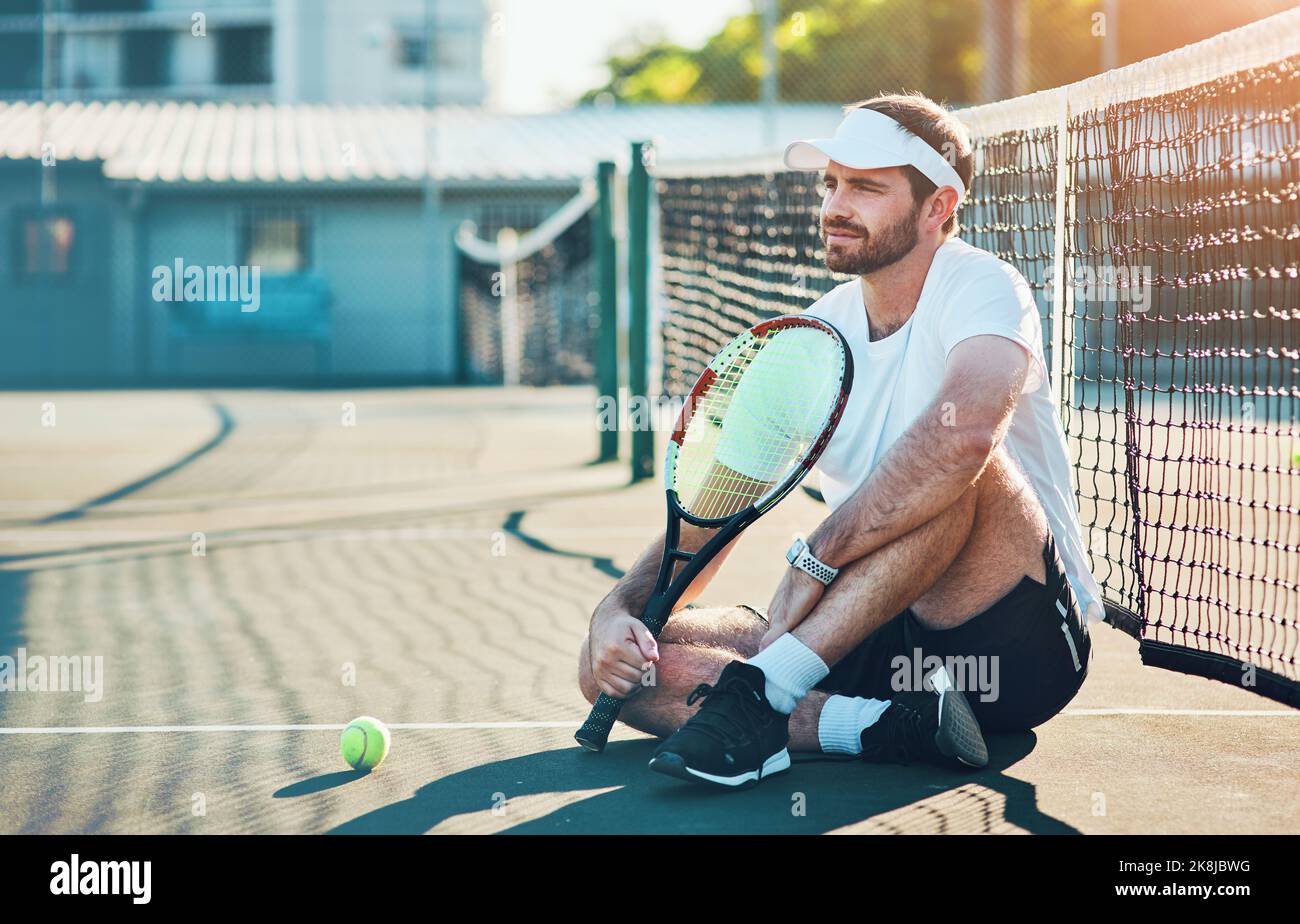 C'était mon rêve de devenir une superstar du tennis. Un jeune sportif assis sur un court de tennis. Banque D'Images