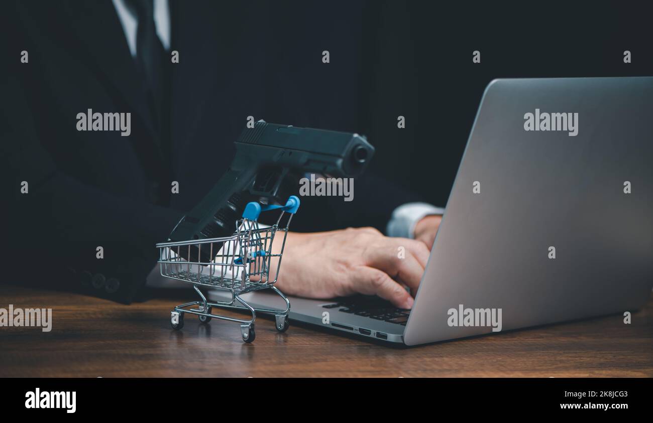 Acheter un pistolet à la boutique en ligne, mains des gens d'affaires dactylographiant sur le clavier d'ordinateur pour acheter un pistolet sur le site Web ou les médias sociaux, Panier Banque D'Images