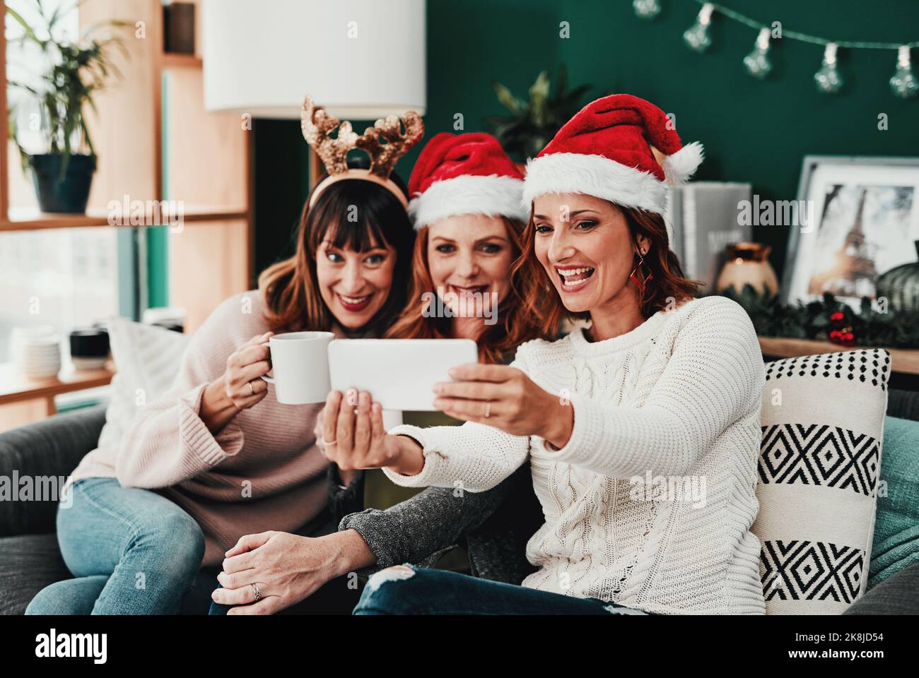 Nous avons l'air fantastique. Trois belles femmes d'âge moyen prenant des autoportraits avec un téléphone portable à la maison pendant Noël. Banque D'Images