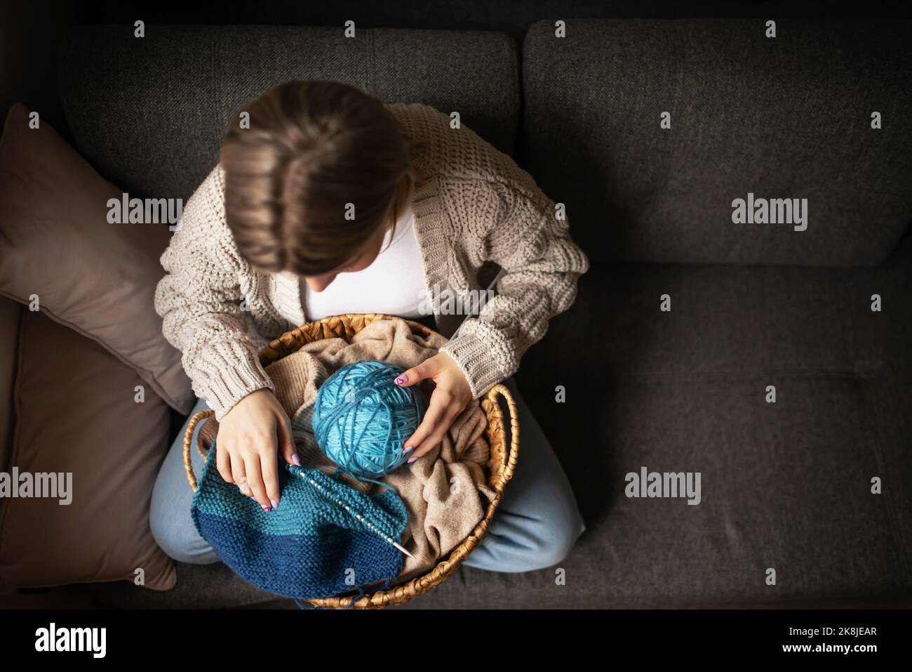 Adulte femme attirante à la maison dans l'activité de tricotage de travail utilisant la laine colorée.Les femmes sont heureuses et détendues et apprécient de passer du temps à l'intérieur sur le canapé.Coudre j Banque D'Images