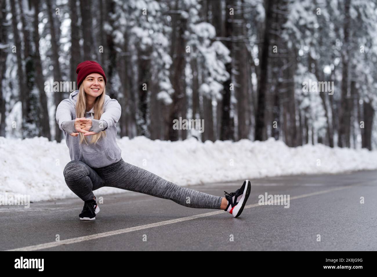 Belle jeune femme sport doing stretching fitness exercise en forêt d'hiver Banque D'Images